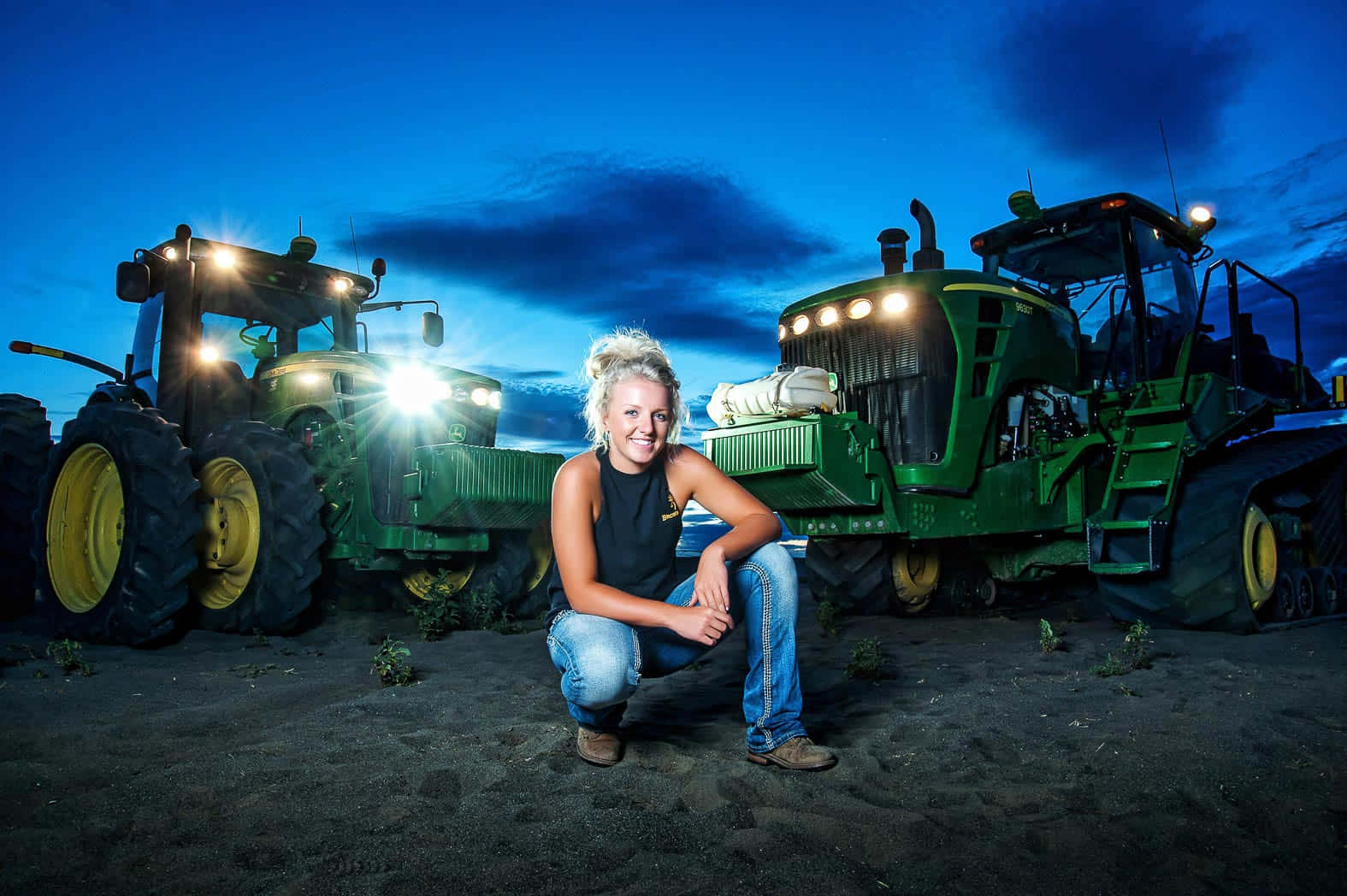A Woman Kneeling In Front Of Two Tractors Wallpaper