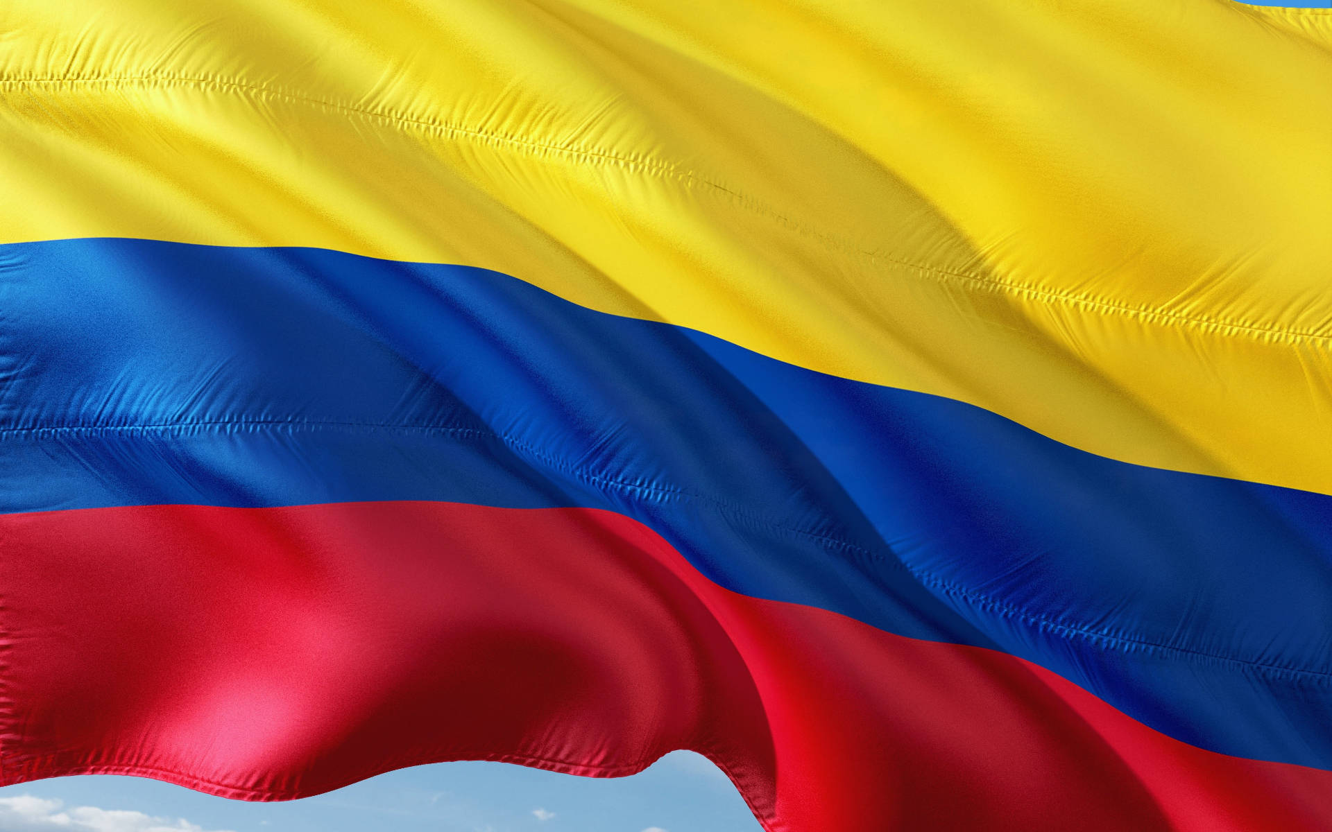Majestic Colombian Flag Waving Under the Open Sky Wallpaper