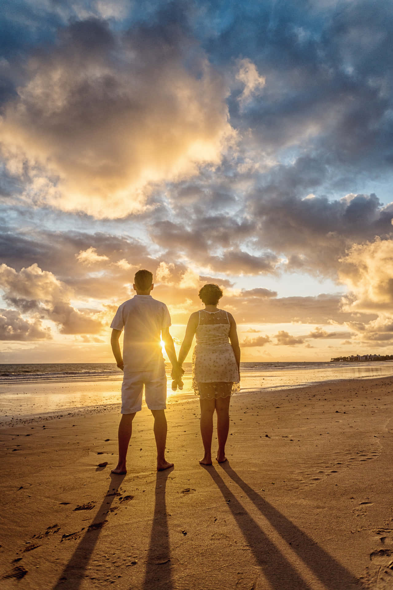 Couple At Beach Holding Hands Under Clouds Picture