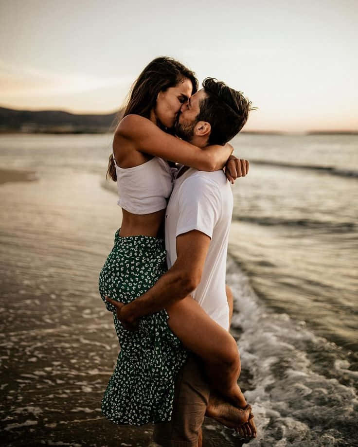 Couple At Beach Kissing While Carrying On Waves Picture