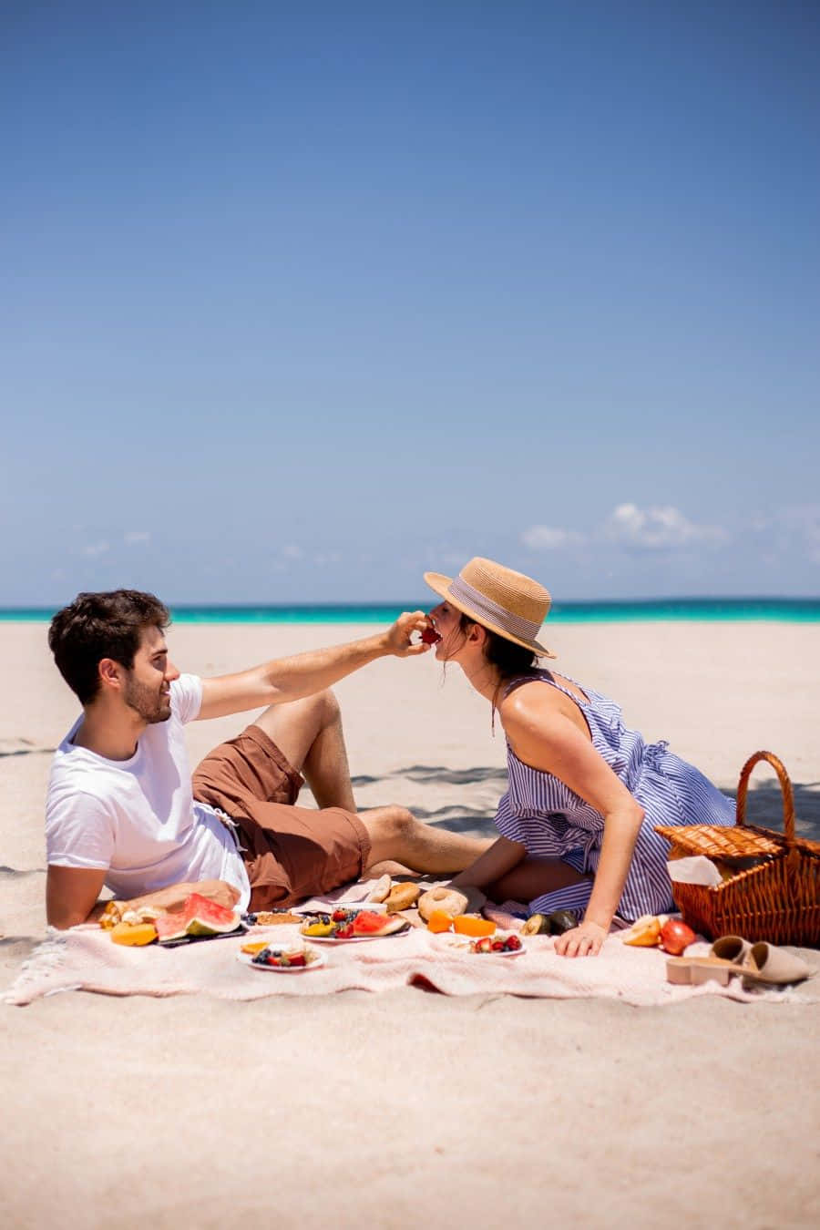 A Loving Moment: Couple Enjoying a Relaxing Picnic on the Beach Wallpaper