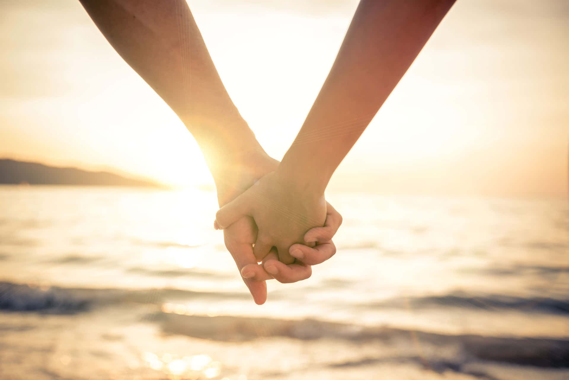 Et par, der holder hinandens hænder ved stranden billede