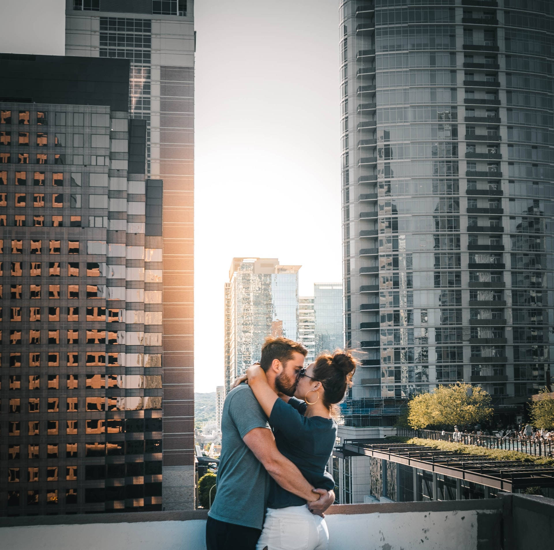Couple Hugging And Kissing On Skyscraper Rooftop Wallpaper