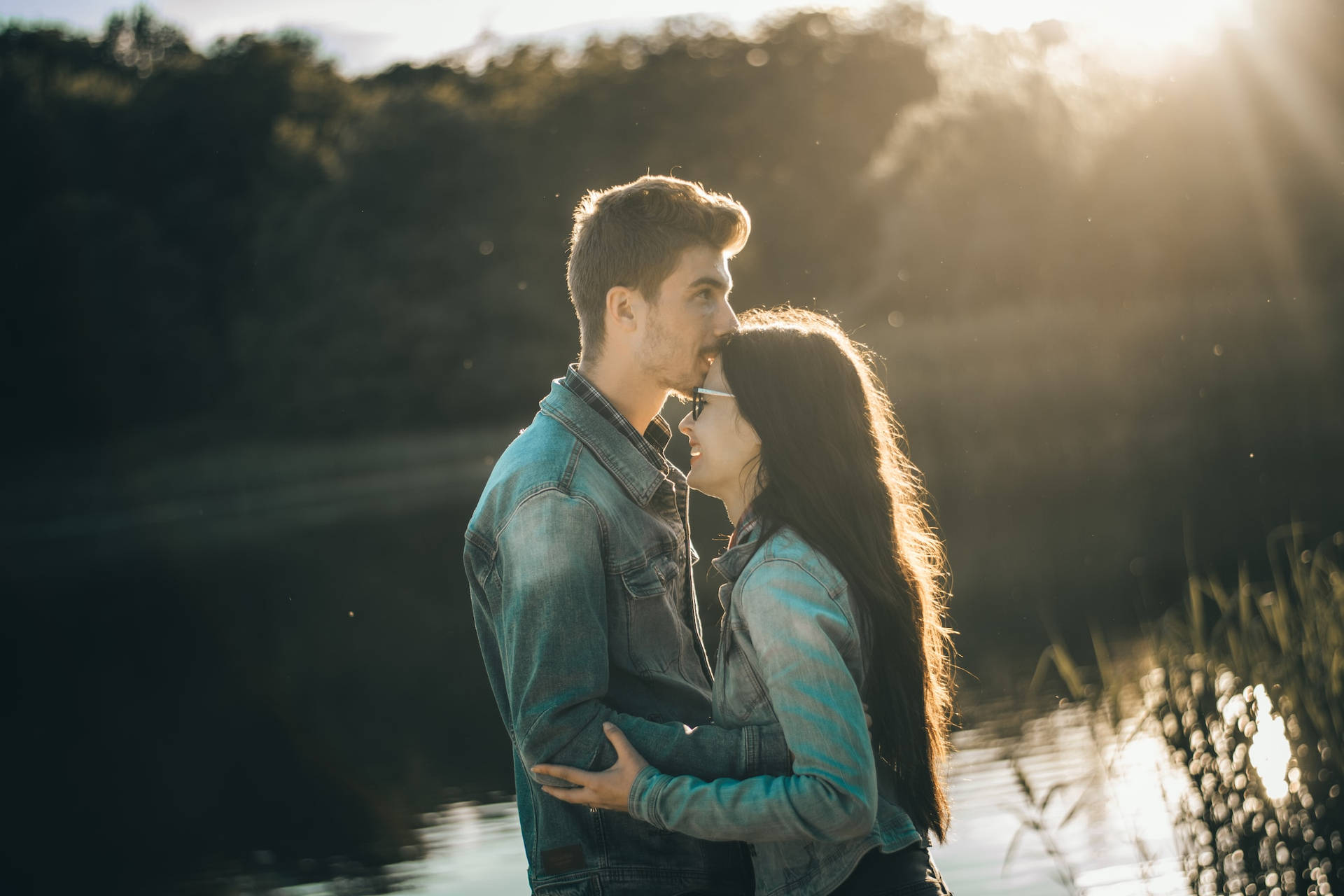 Par krammer med kys på panden tæt på floden Wallpaper