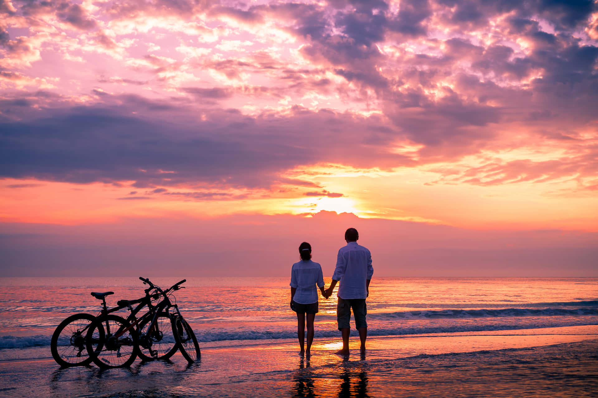 Couple Sunset Holding Hands On Beach With Bicycles Picture
