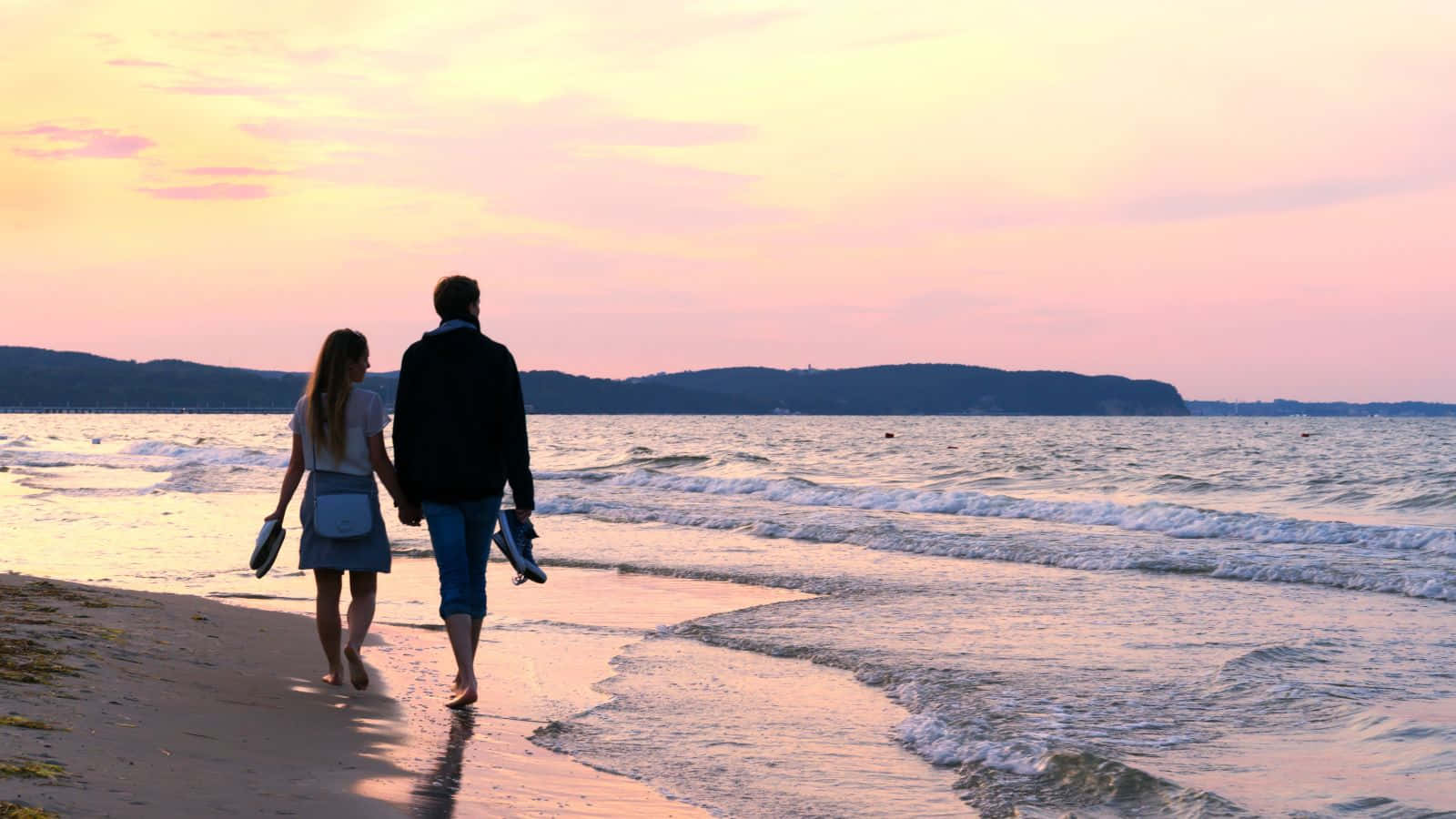 Bildeines Paares Bei Sonnenuntergang, Das Am Strand Spazieren Geht.