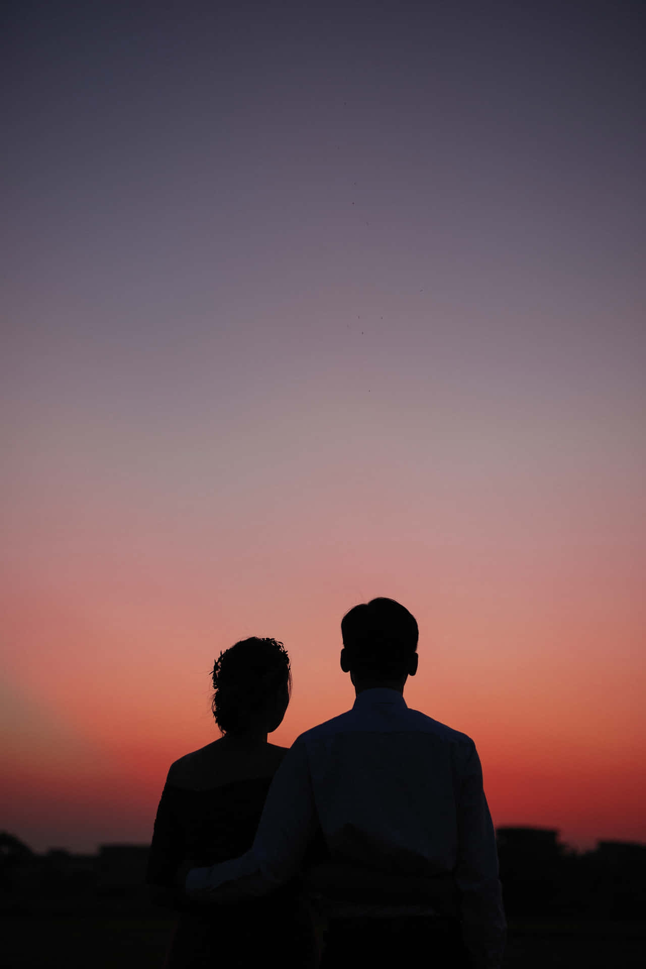 Bildvon Einem Paar, Das Unter Einem Himmel Mit Sonnenuntergangsschatten Steht.