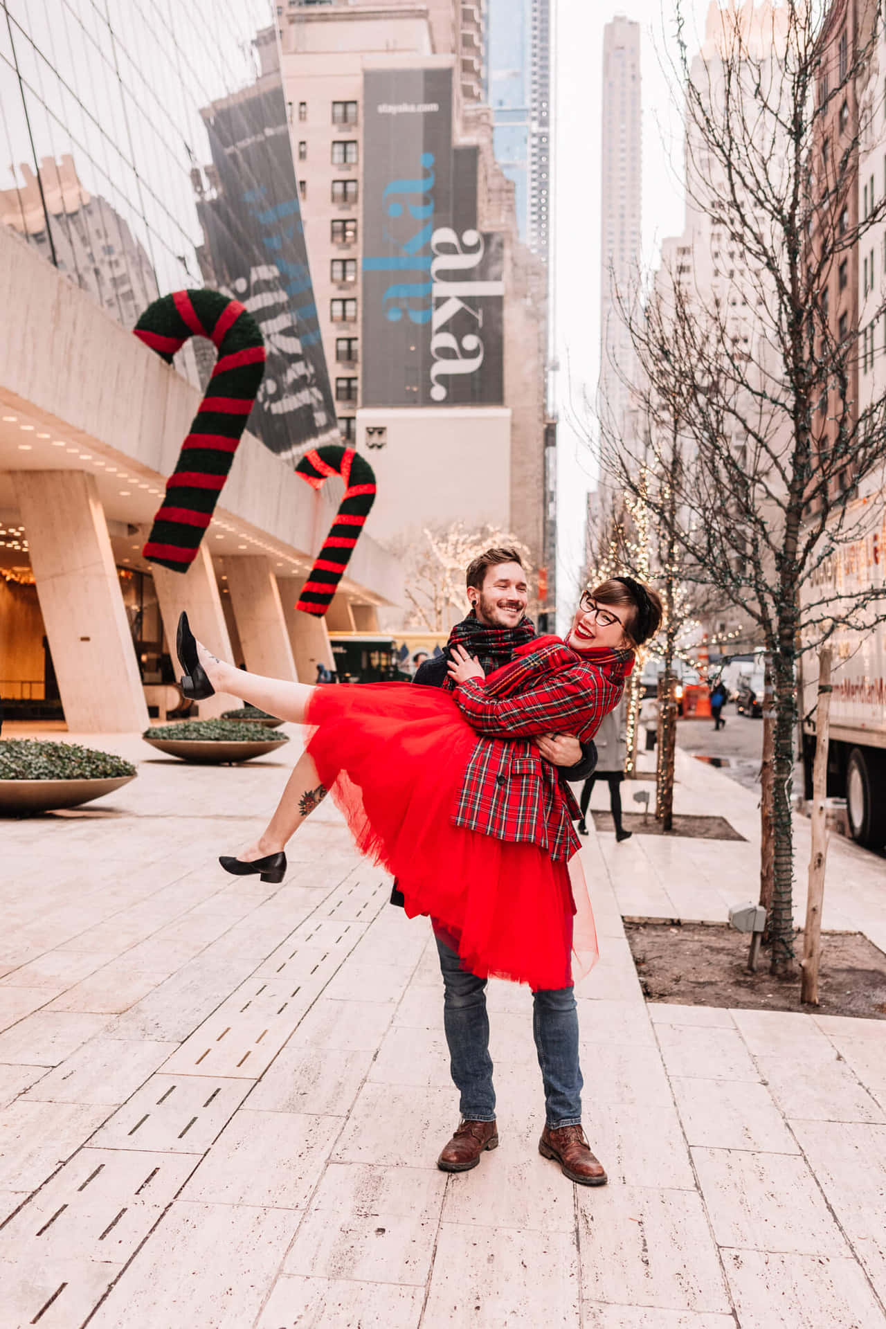 A Couple In A Red Dress Is Holding Hands In Front Of A City