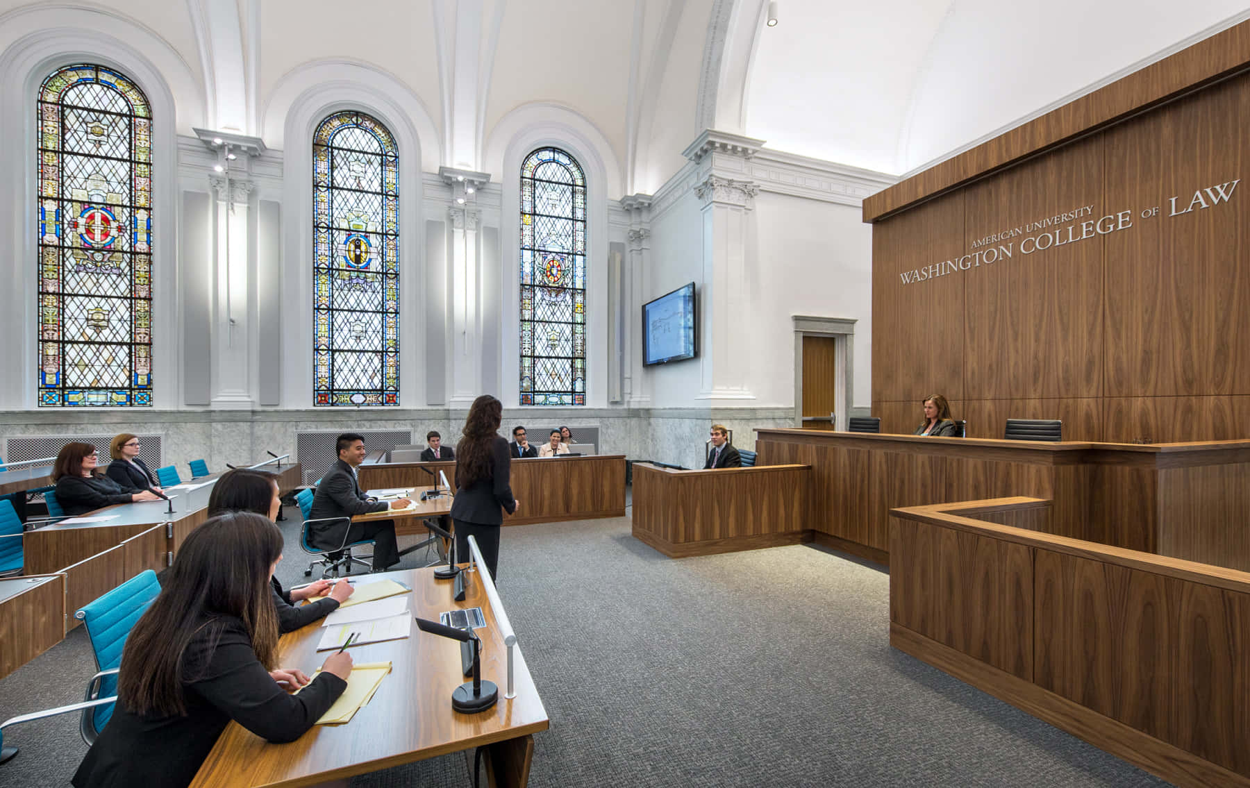 A Courtroom With People Sitting At Desks