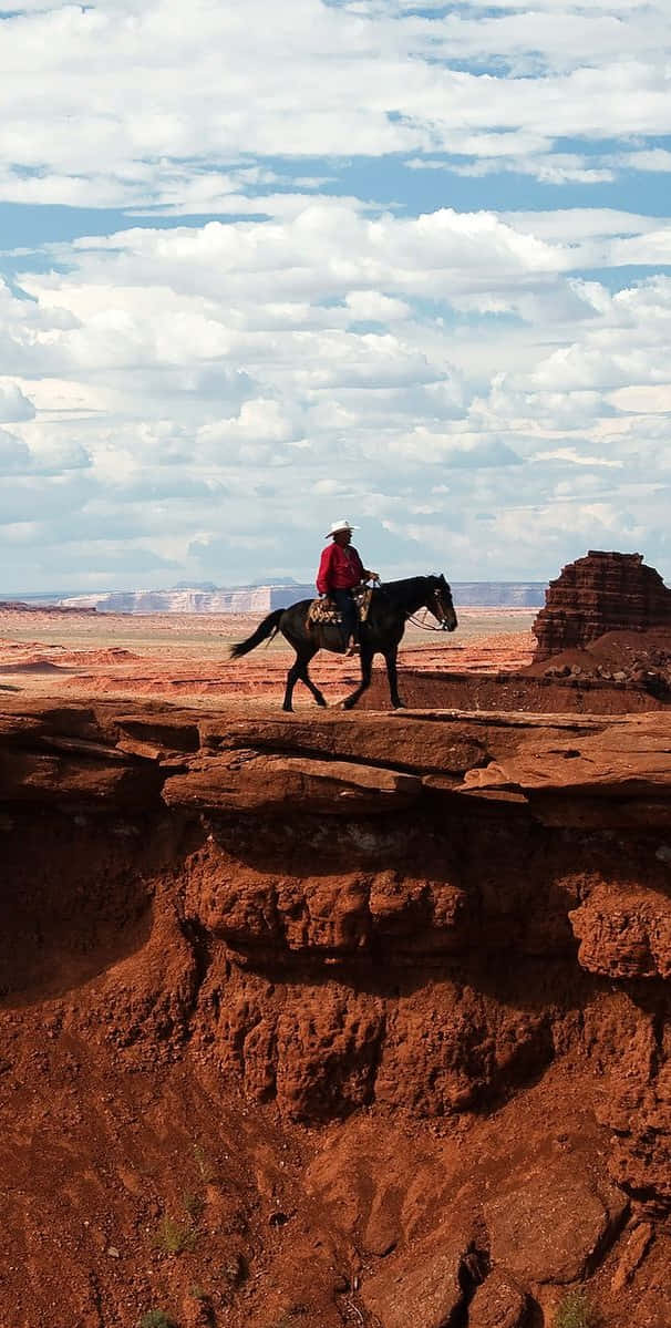 En mand rider på en hest på en klippe. Wallpaper