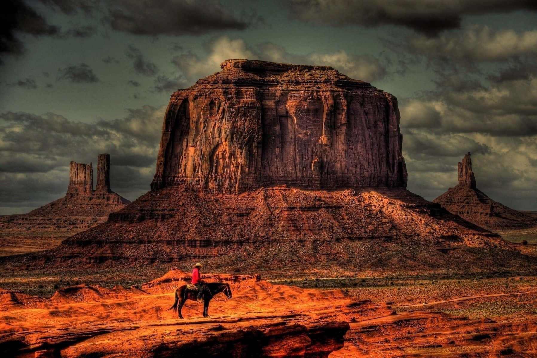 A group of cowboys riding horses through a canyon landscape