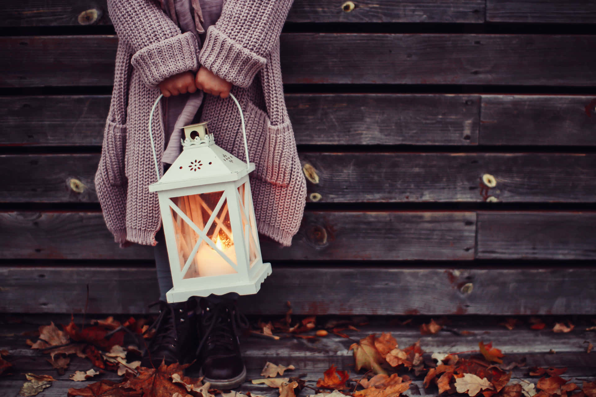 En kvinde holder en lampe i efteråret Wallpaper