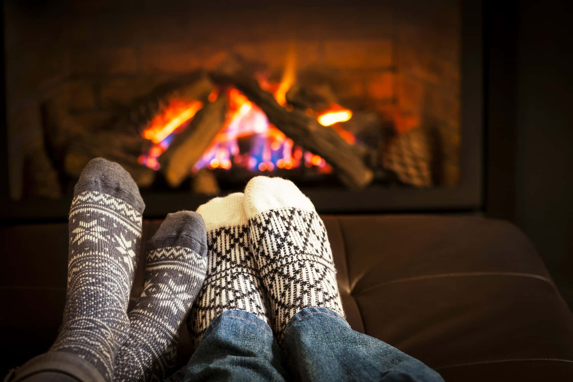 Two People Sitting In Front Of A Fireplace With Their Feet In Socks Wallpaper
