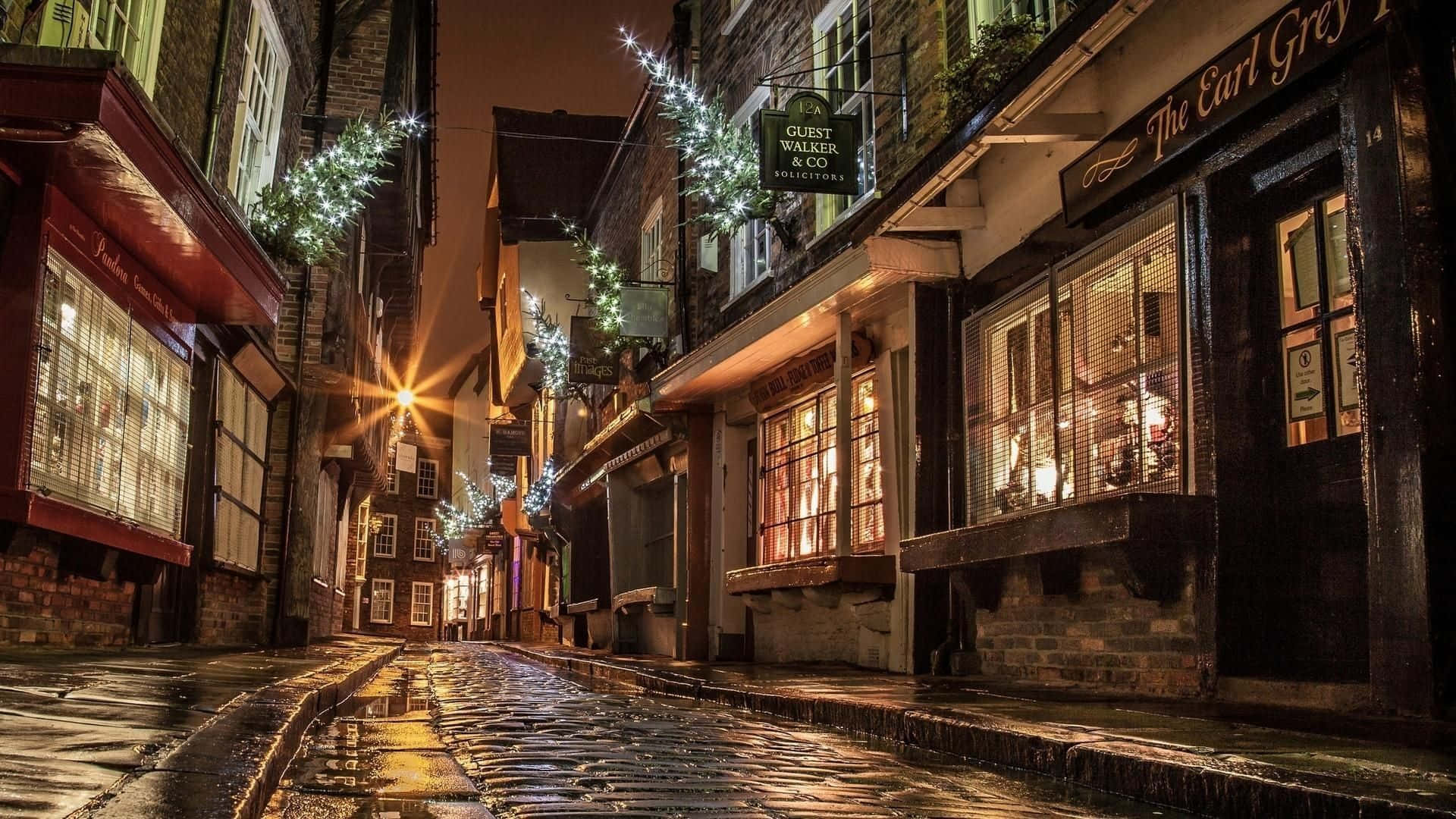 A Cobbled Street With Lights And Decorations Wallpaper