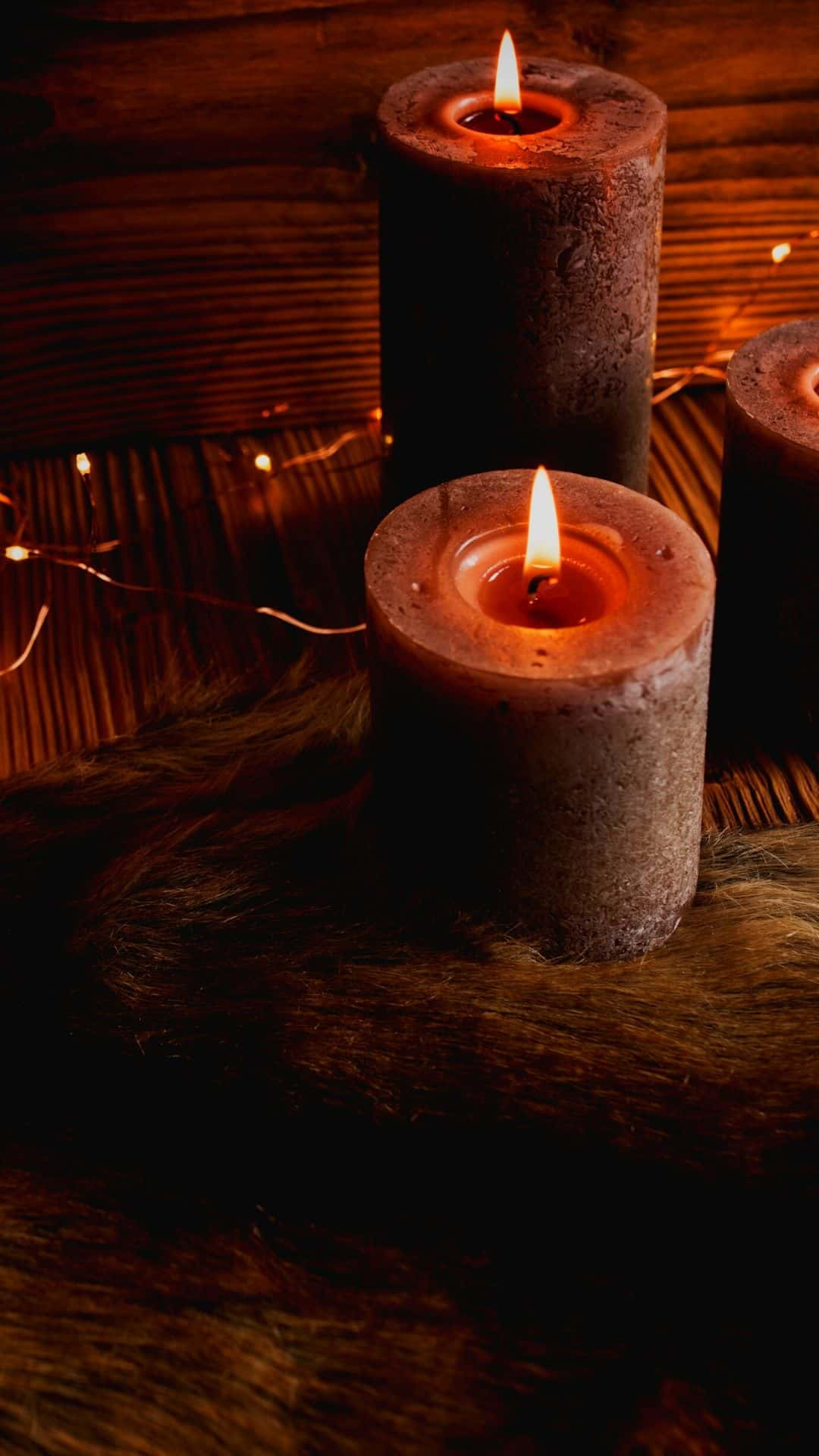 Three Candles Are Lit On A Wooden Table Wallpaper