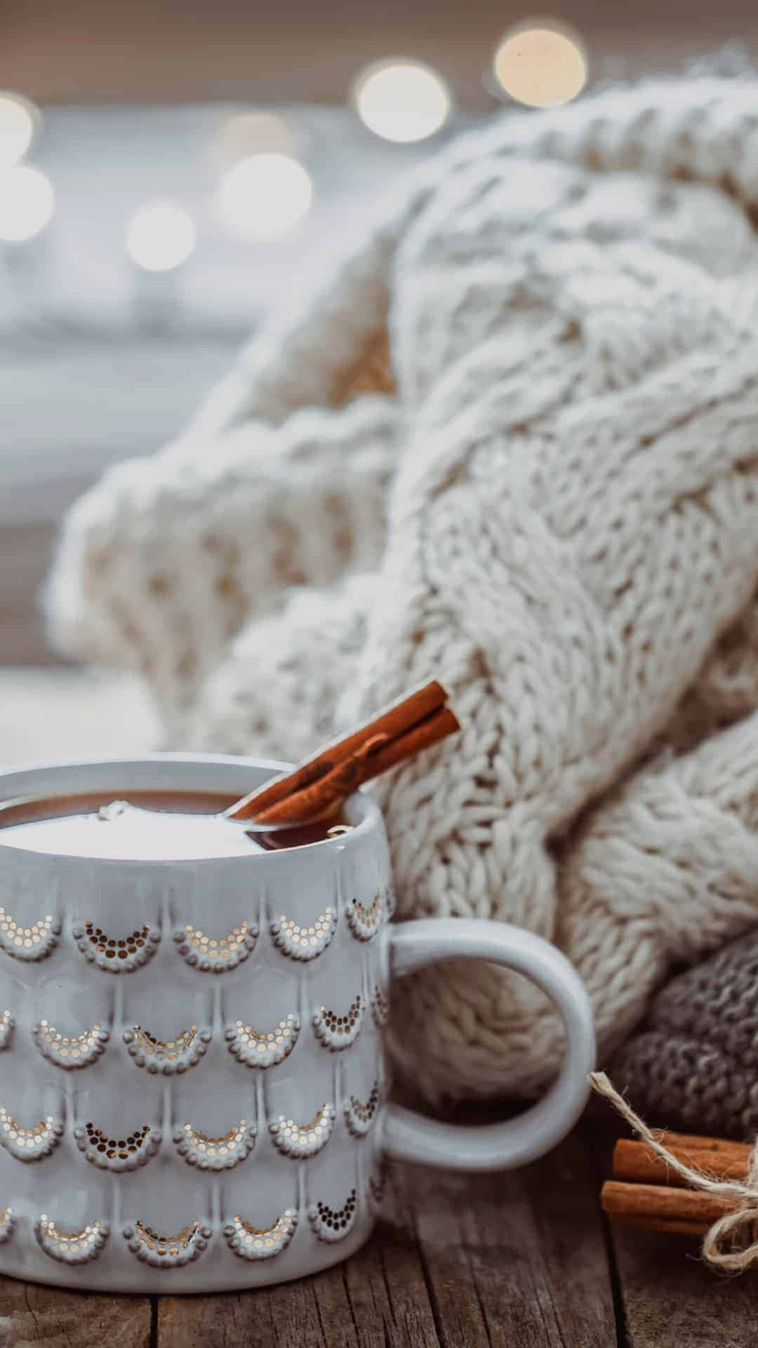 En kop varm chokolade med kanelstænger og en strikket trøje Wallpaper