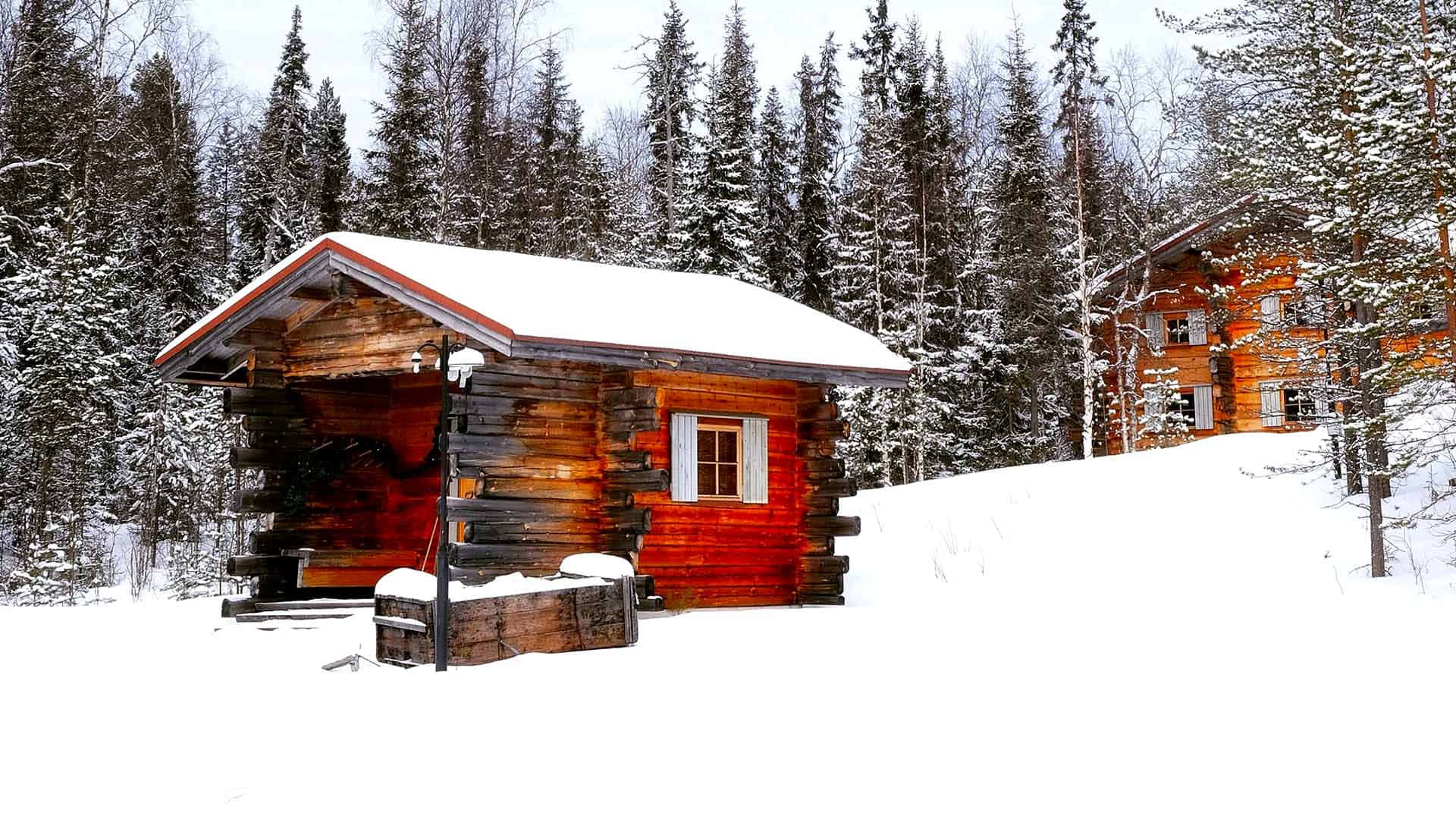 A peaceful snowy retreat at a cozy winter cabin nestled in the forest Wallpaper