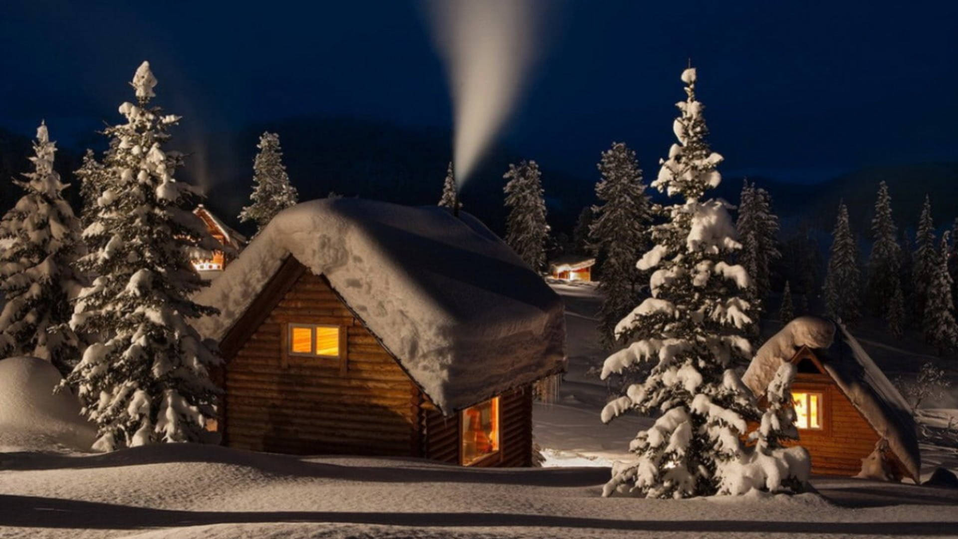 Cozy Winter Cabins On A Snowy Evening Wallpaper