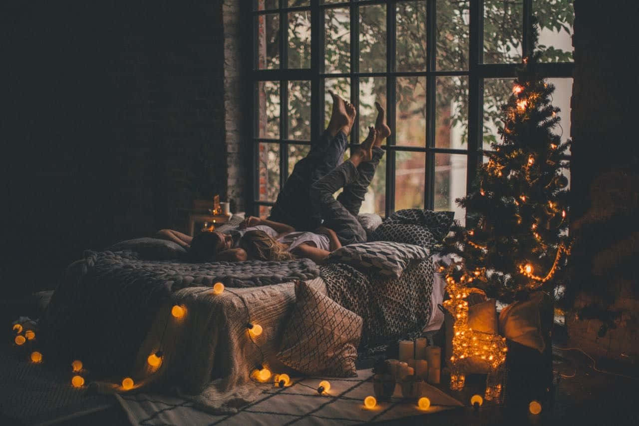 A Woman Laying On A Bed With Christmas Lights Wallpaper