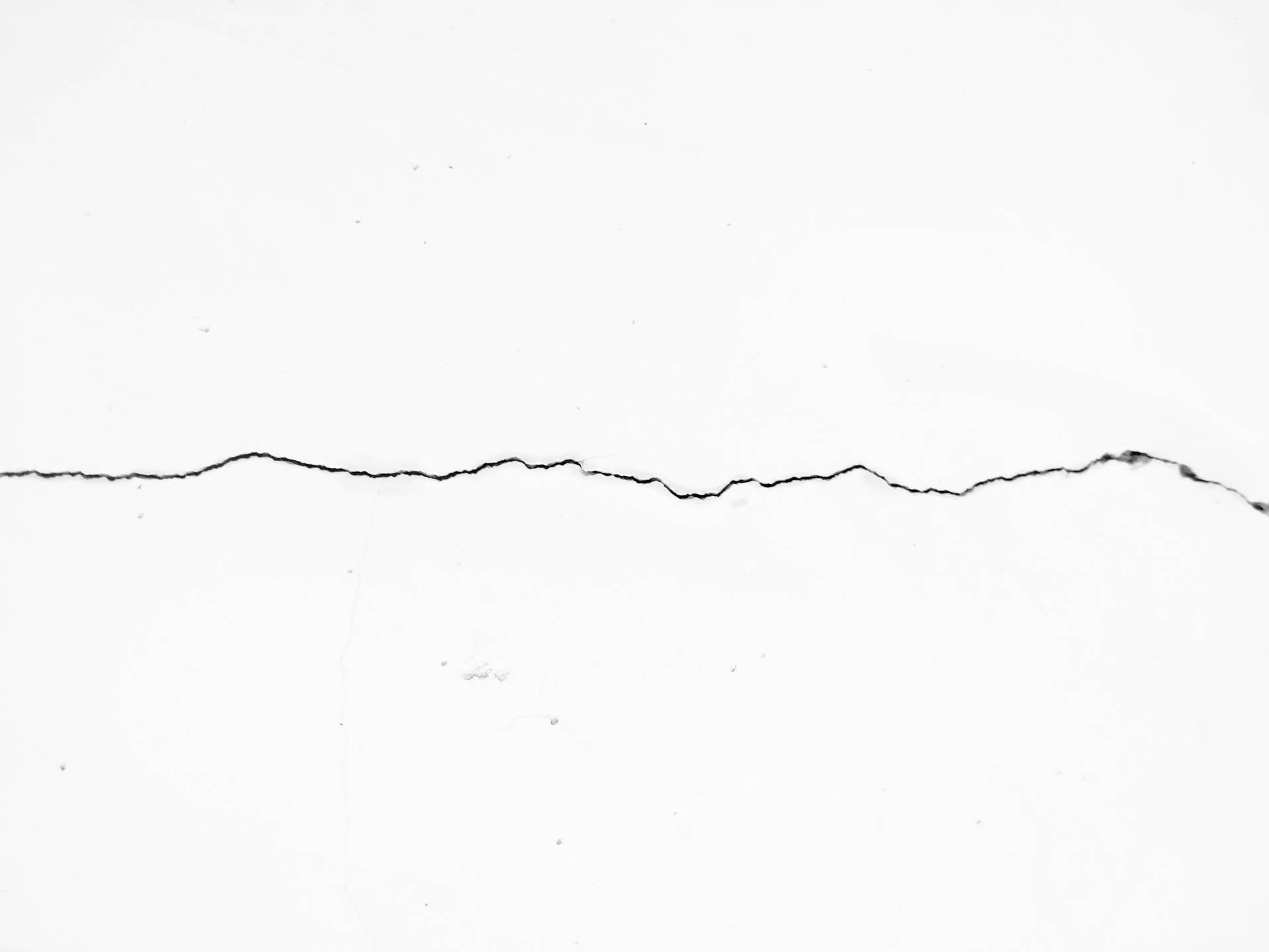 Minimalist wallpaper of cracked black line on pure solid white concrete wall.  