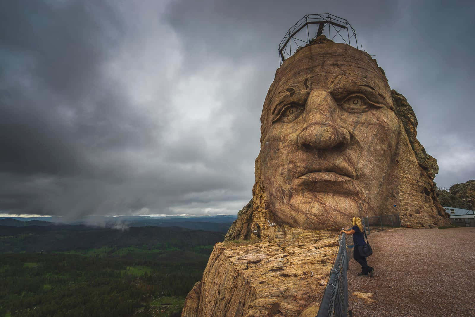 A Man Is Standing On Top Of A Mountain With A Large Head