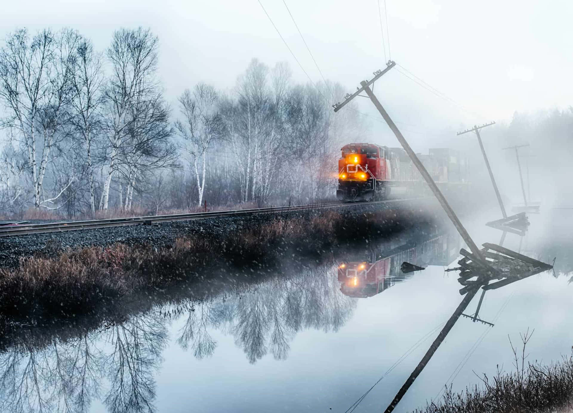 A Train Is Traveling Down A Track Near A River