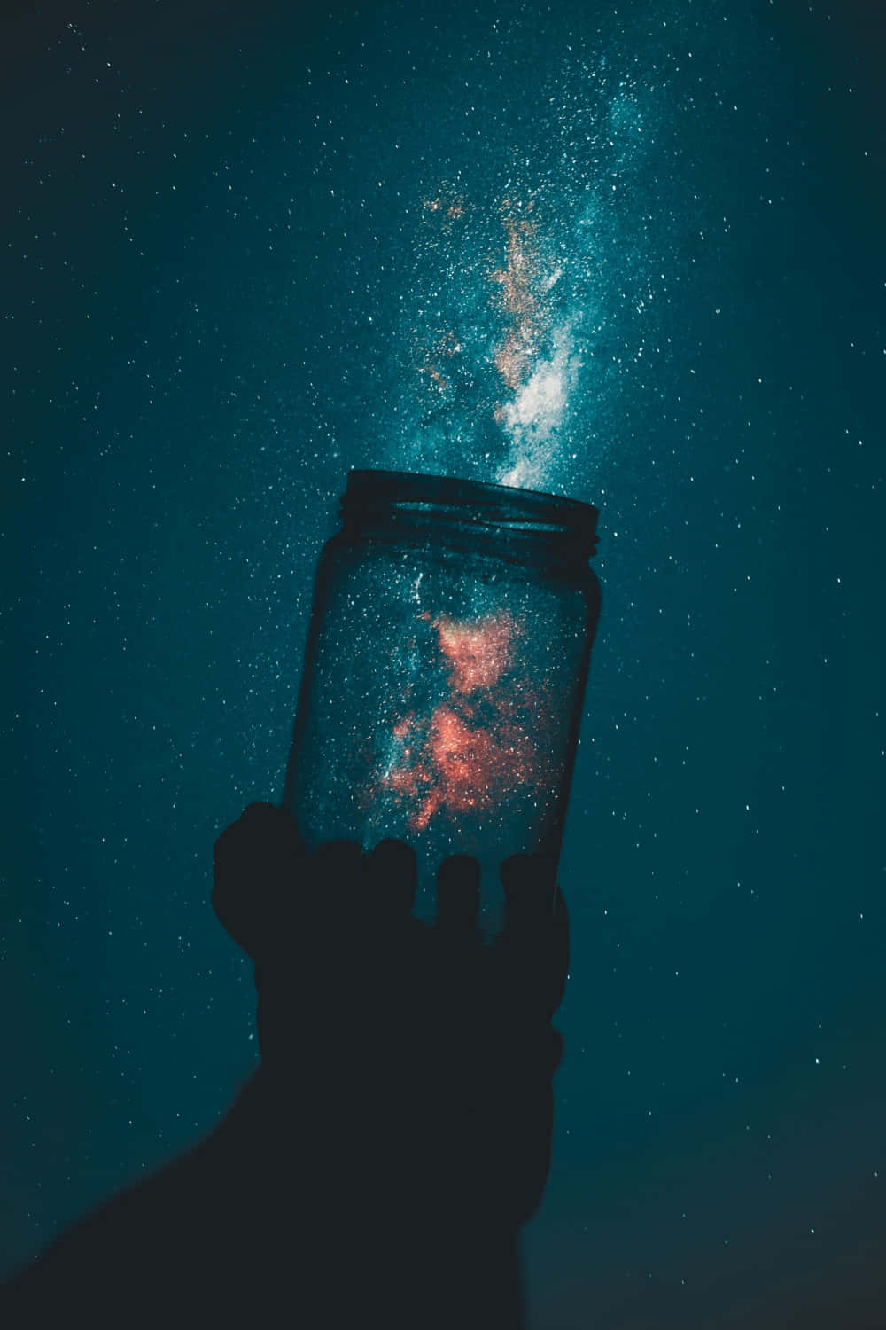 a person holding a jar with stars in the sky