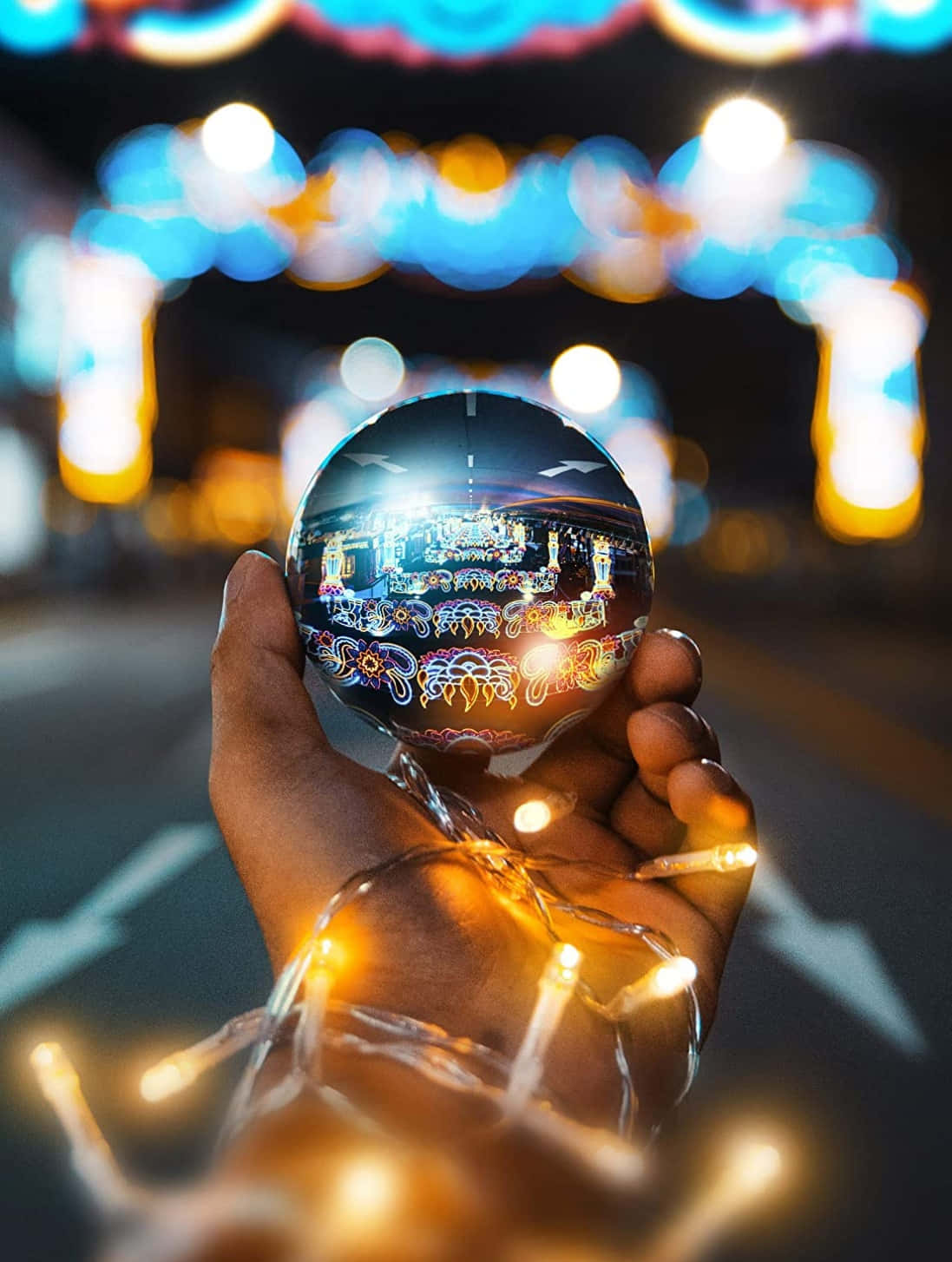 A Hand Holding A Christmas Ball With Lights In It