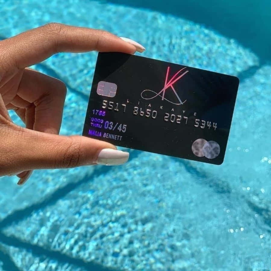A Person Holding A Credit Card In Front Of A Pool