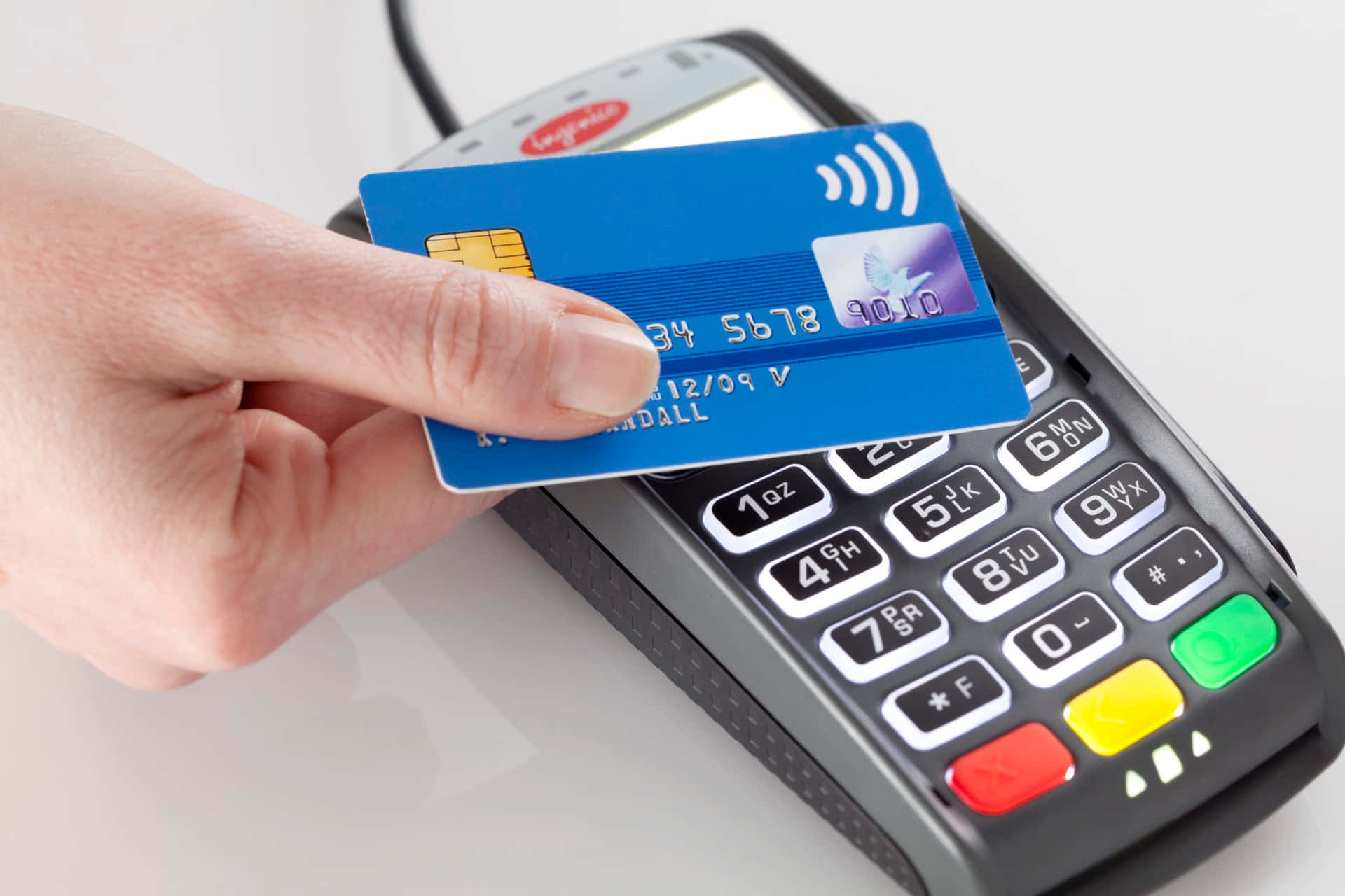 Enperson Håller I Ett Kreditkort Framför En Betalterminal.