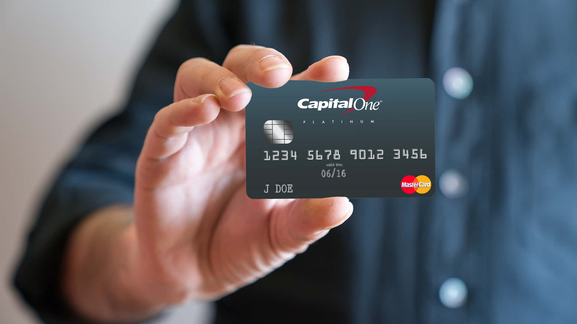 A Man Holding Up A Capital One Credit Card