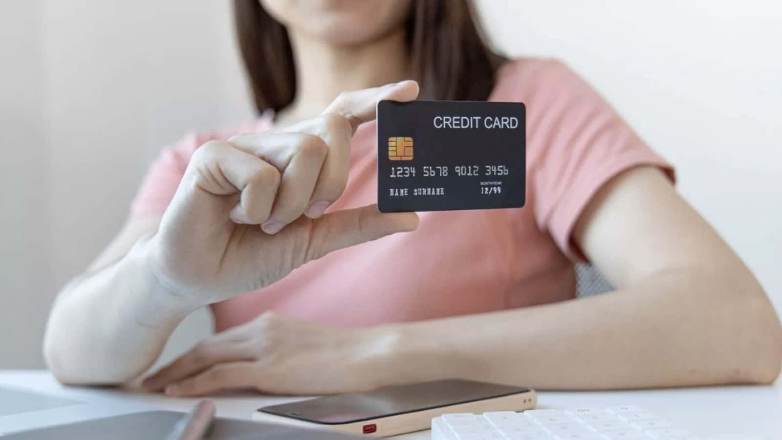 Enkvinna Håller Upp Ett Kreditkort Vid Ett Skrivbord.