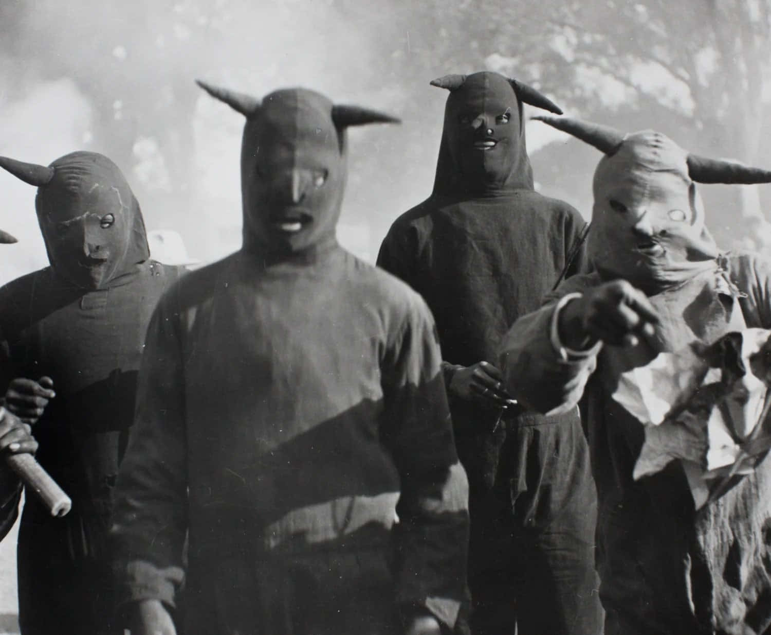 A Group Of Men In Masks Standing In A Field