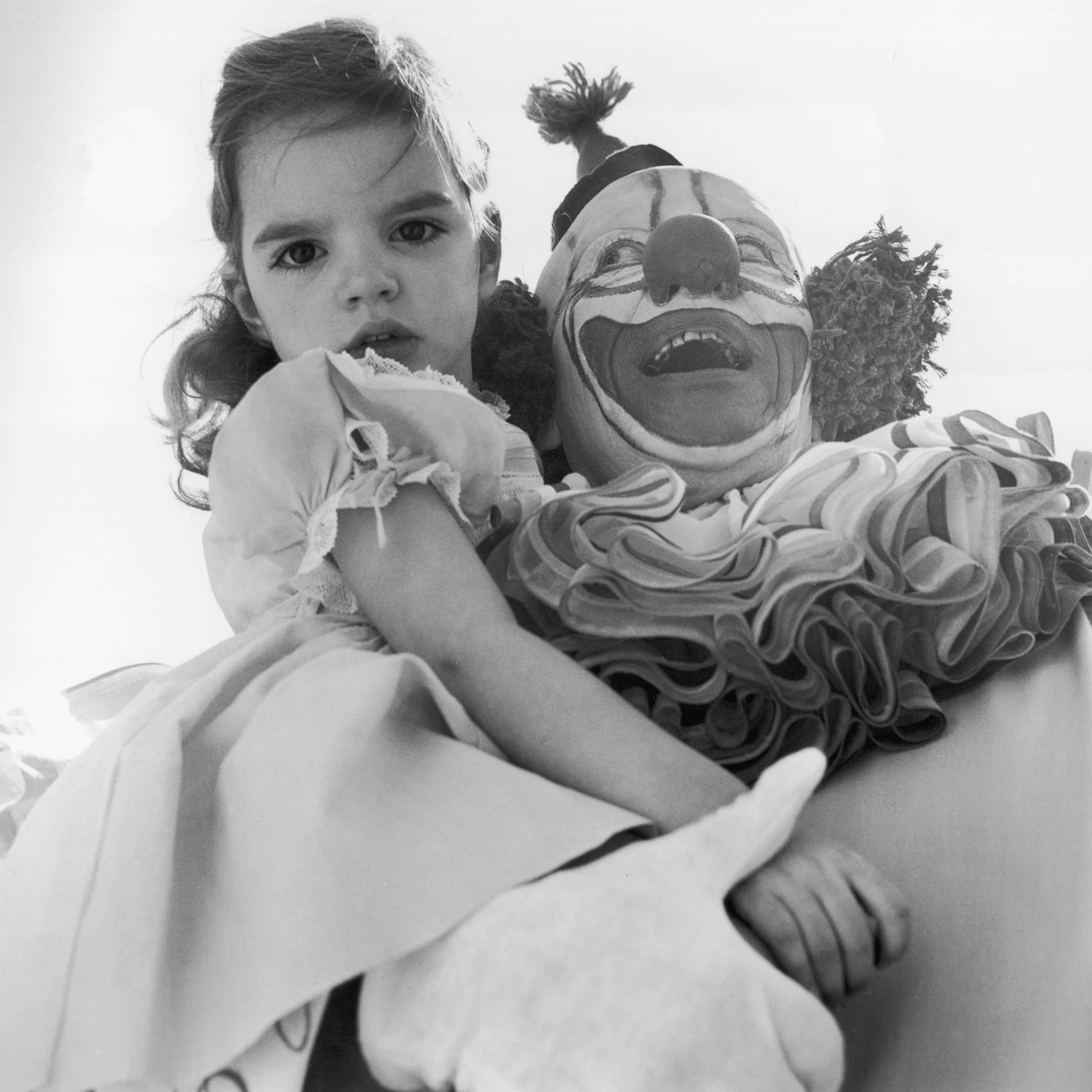 A Young Girl Is Holding A Clown