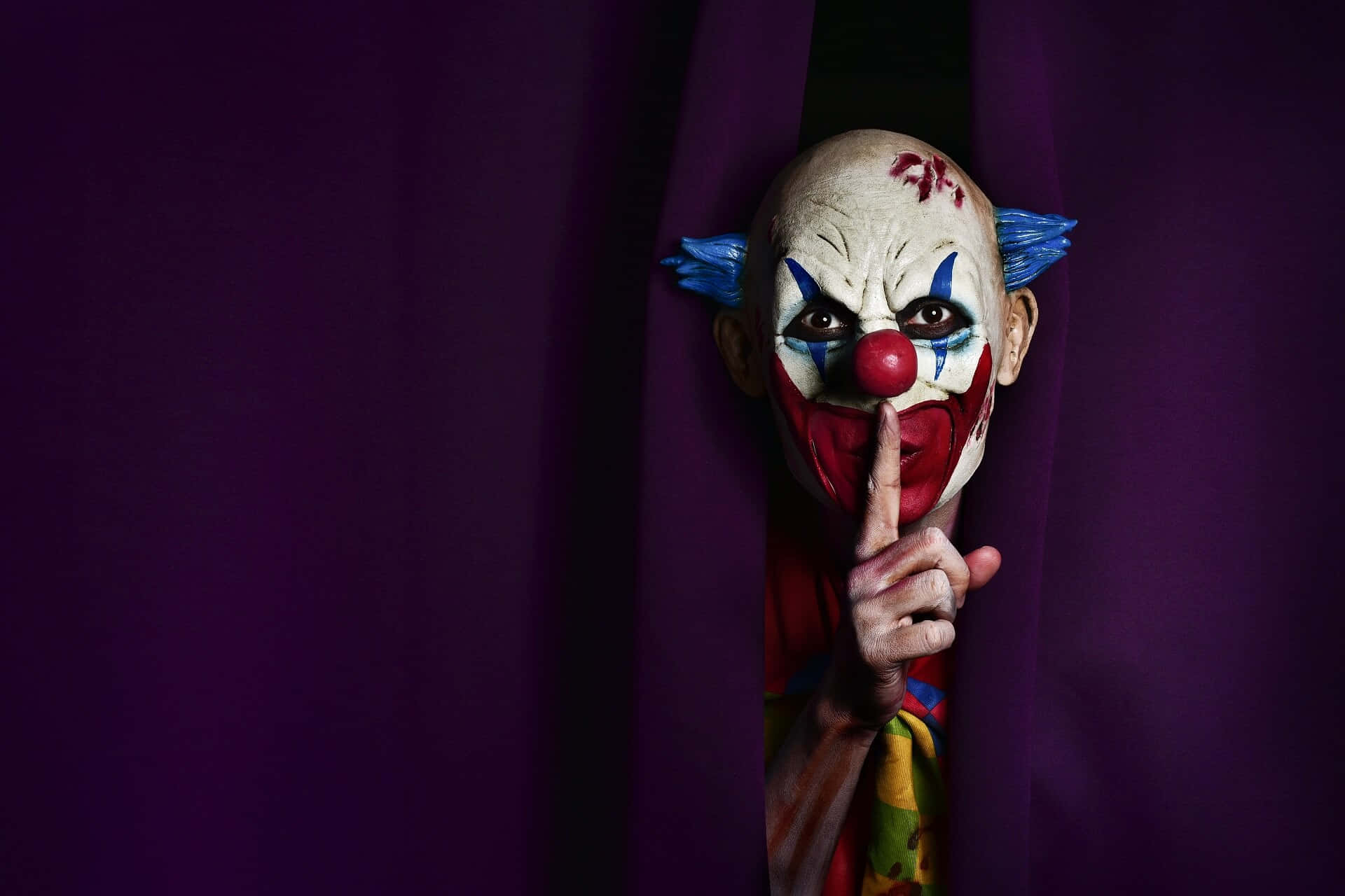 a clown peeking out of a purple curtain