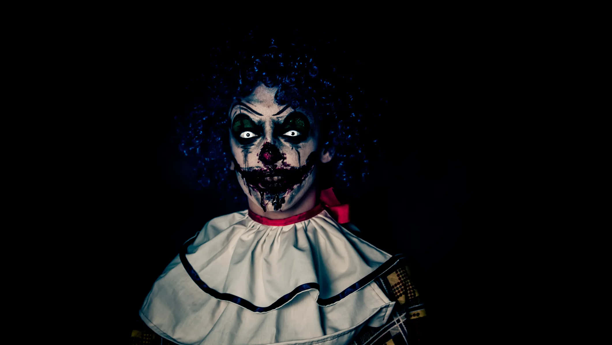 A terrifying clown stares ahead with a menacing smile.