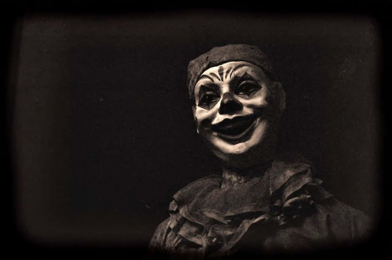 a clown is smiling in a dark room