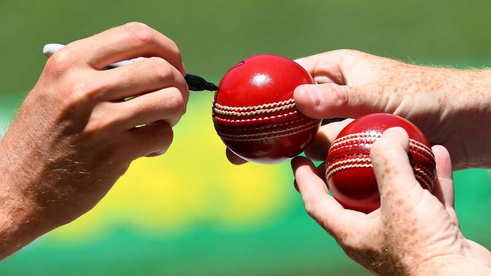 Two People Are Holding Red Cricket Balls
