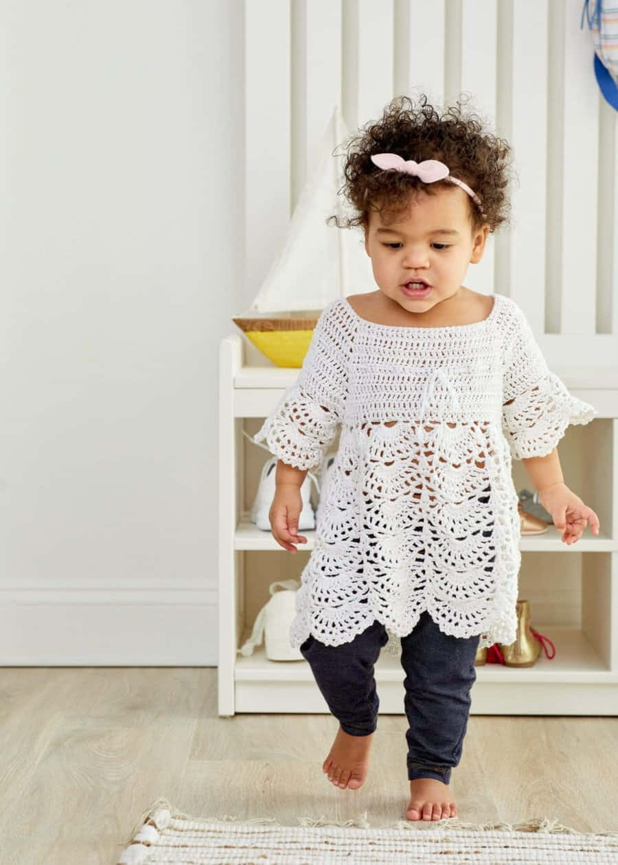 A Baby Girl Wearing A Crocheted Top And Pants