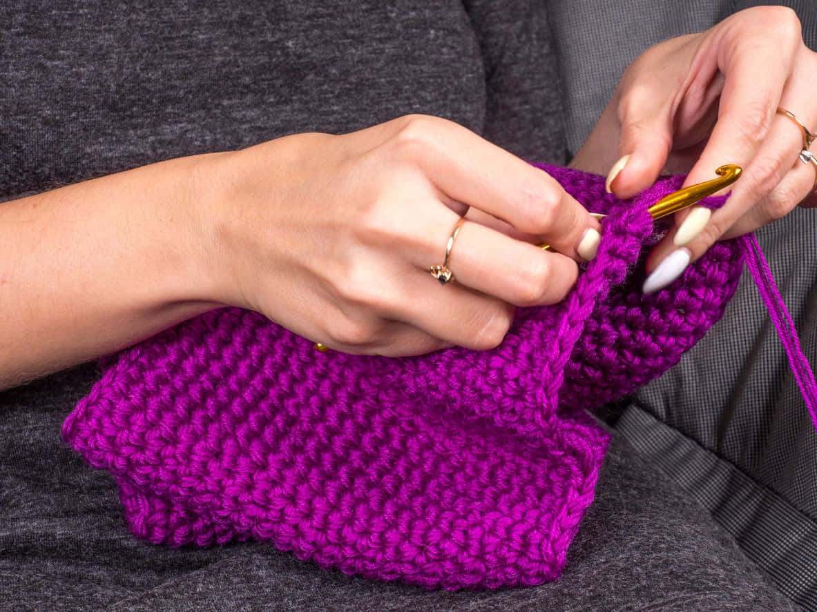 A Woman Knitting A Purple Knitted Bag