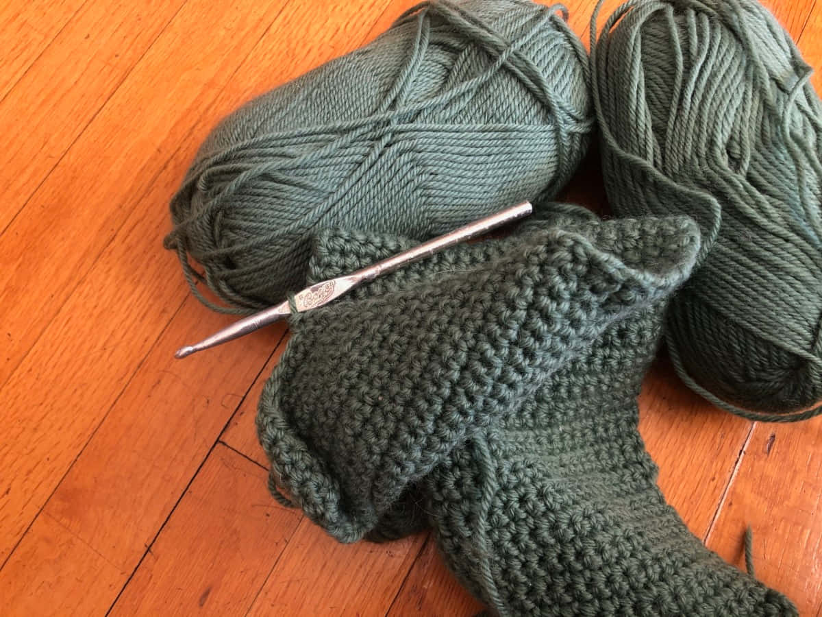 A Green Crocheted Sock And A Knitting Needle