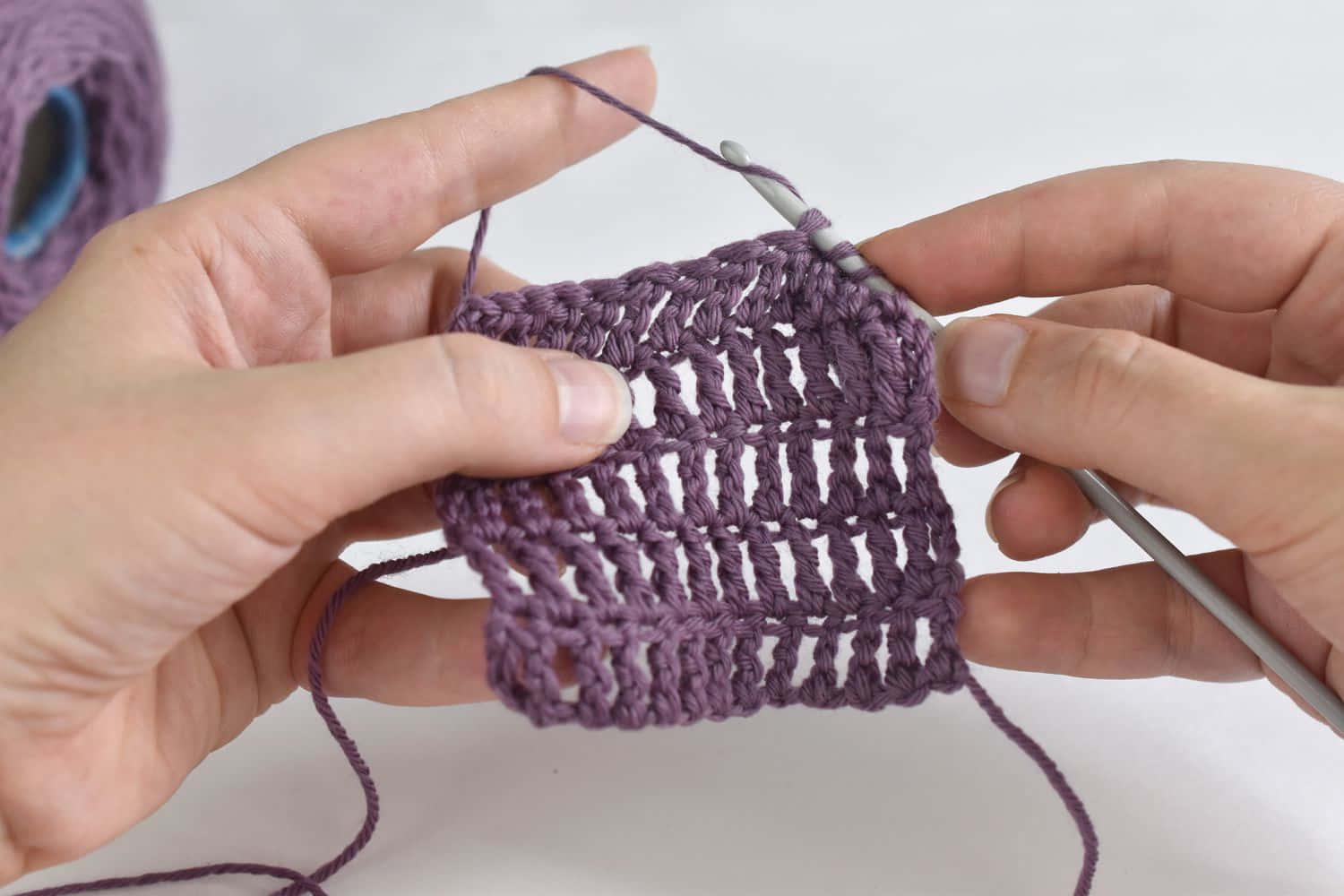 A Person Is Knitting A Purple Crochet Stitch