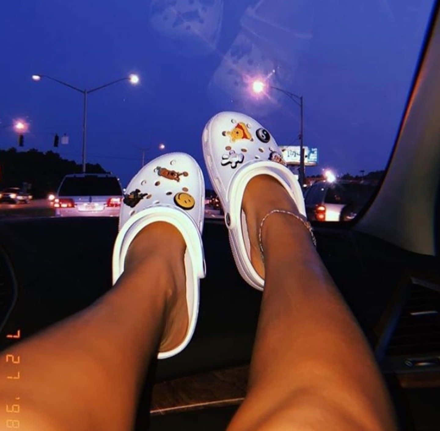 A Woman's Feet Sitting In A Car Wearing White Clogs