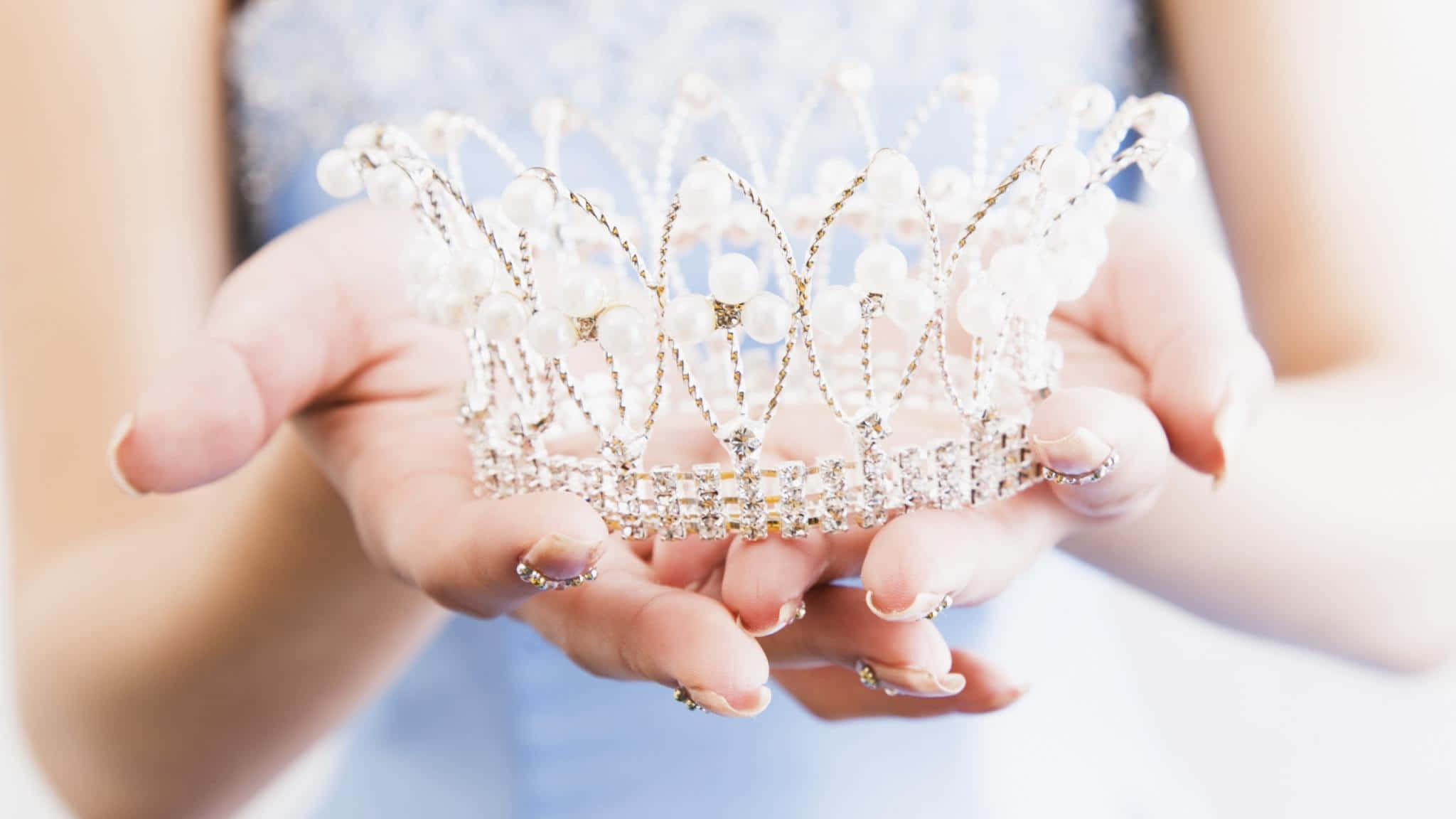 A Woman Is Holding A Crown In Her Hands