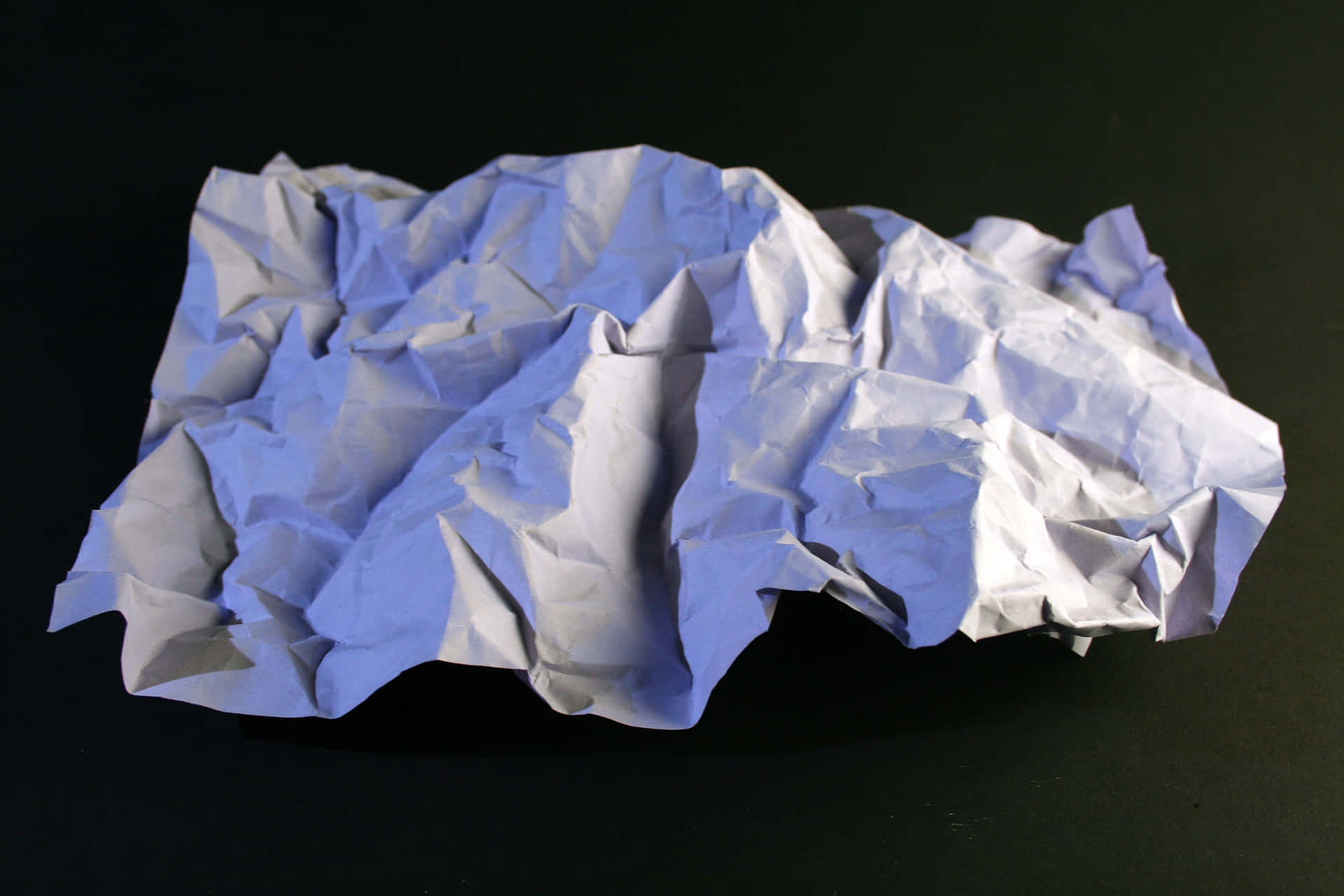A crumpled paper background in blue showing the unique texture and lines of the paper's form.