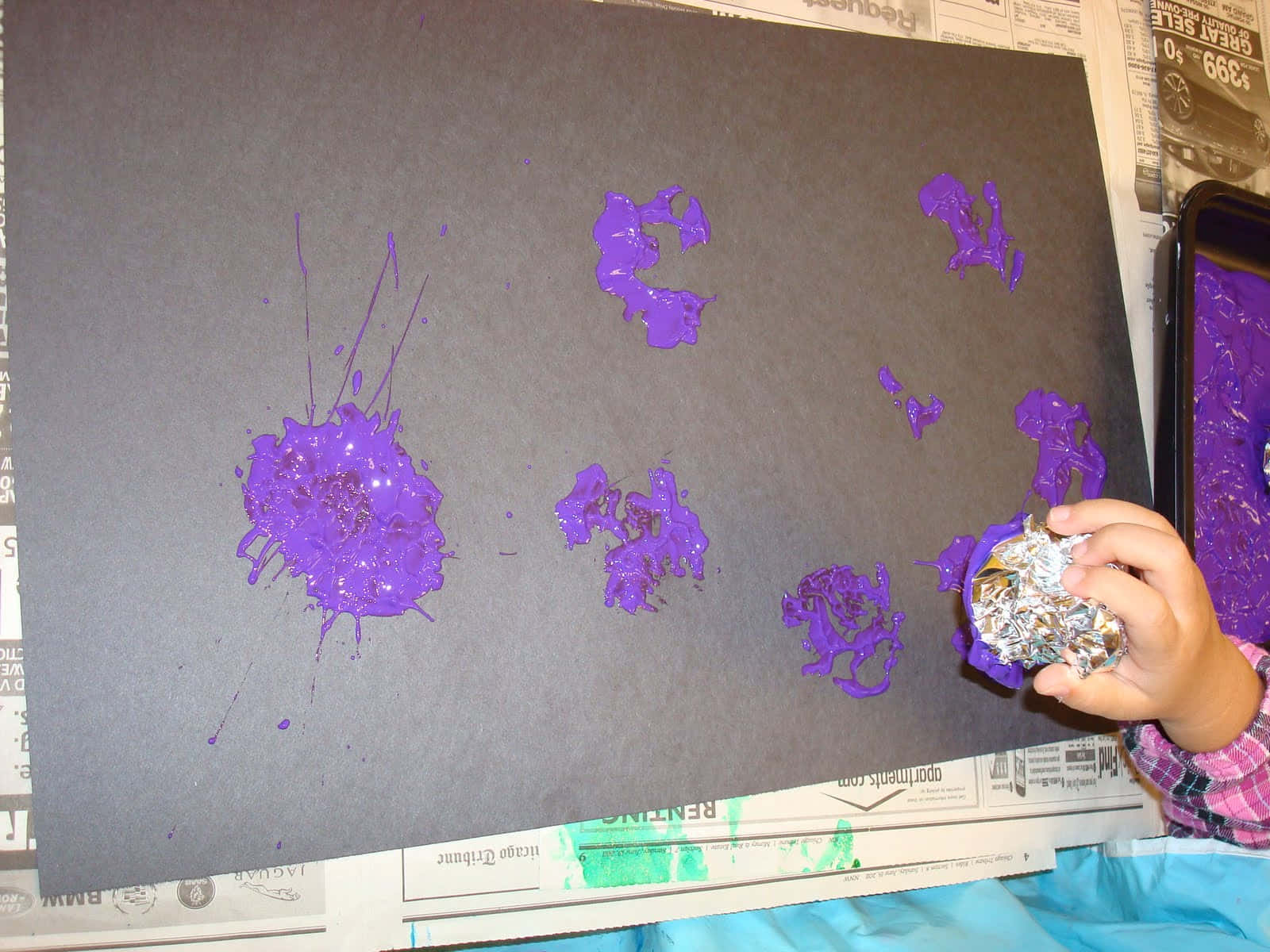 A Child Is Painting Purple And Black On A Piece Of Paper