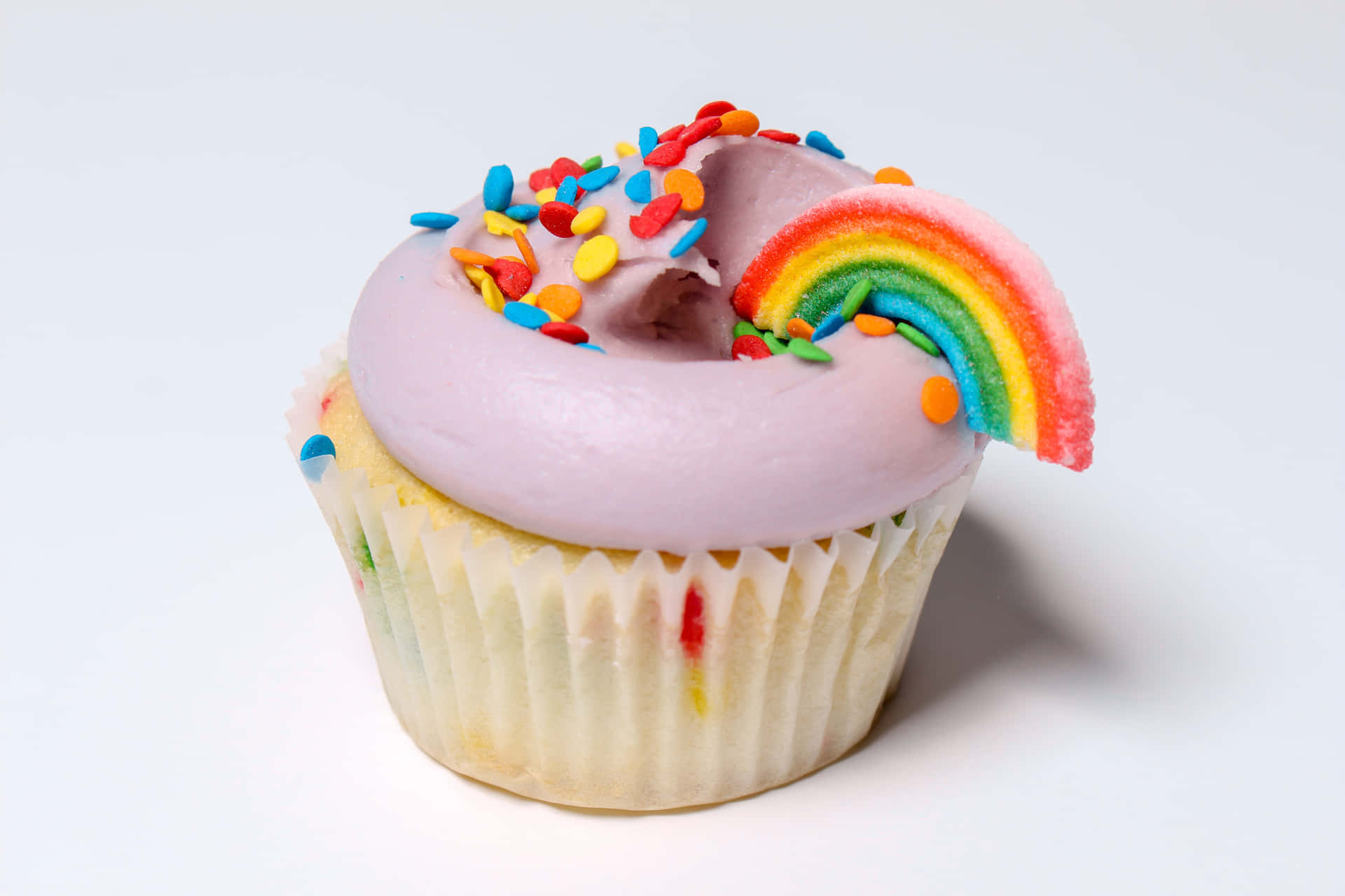 A sugary-sweet cupcake with pink frosting, sprinkled with sprinkles.