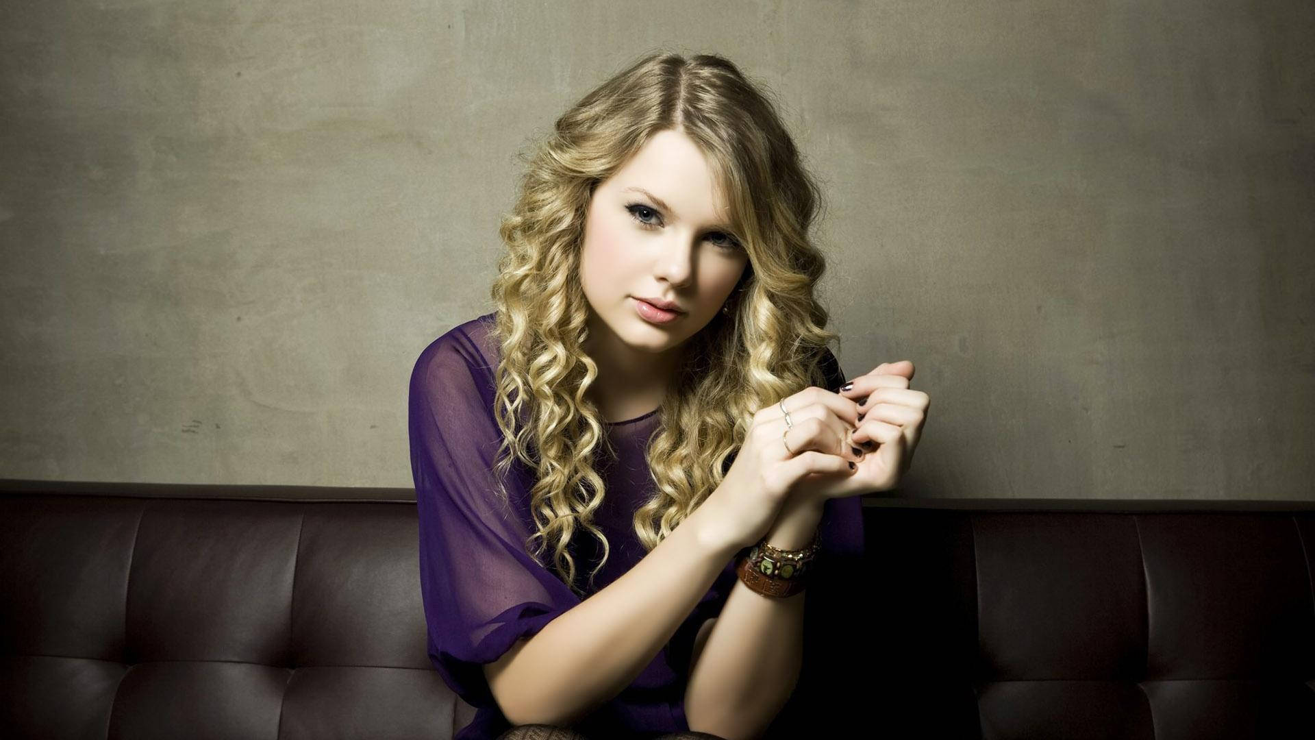 Taylor Swift radiating positive energy with her signature curly hair. Wallpaper