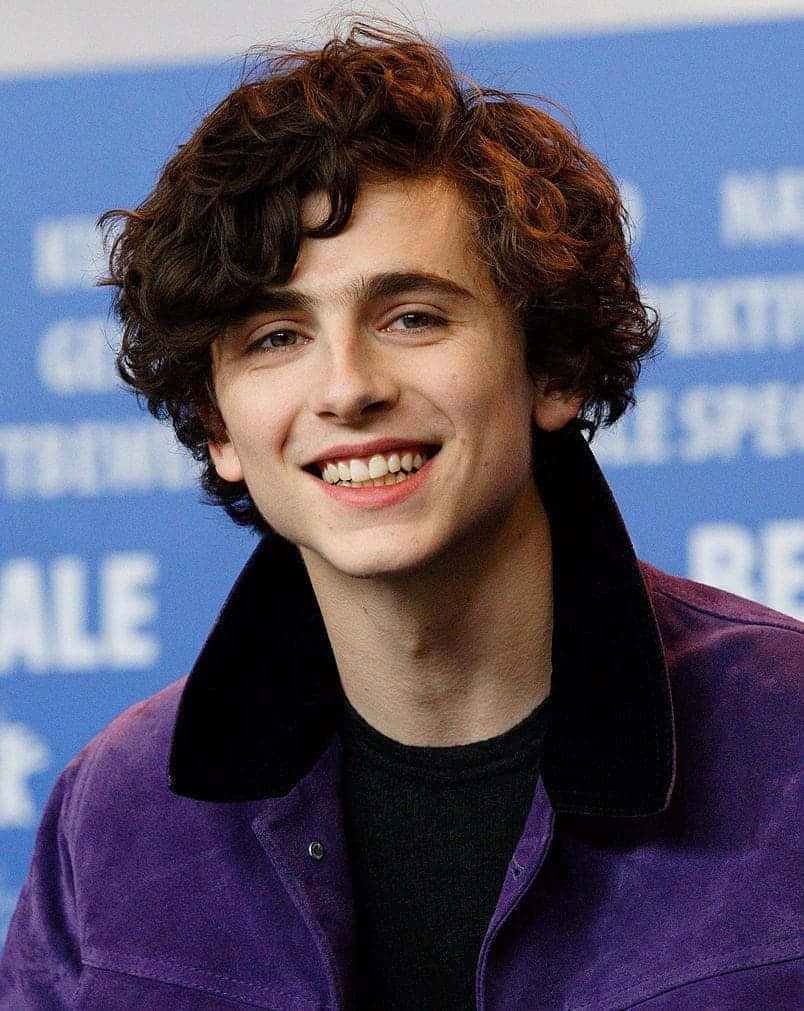 Curly Haired Boy Smiling Purple Jacket Wallpaper