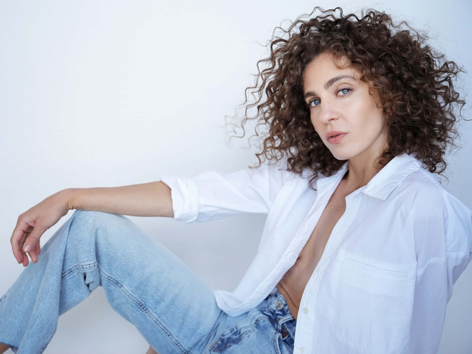 Curly Haired Woman In White Shirt And Jeans Wallpaper